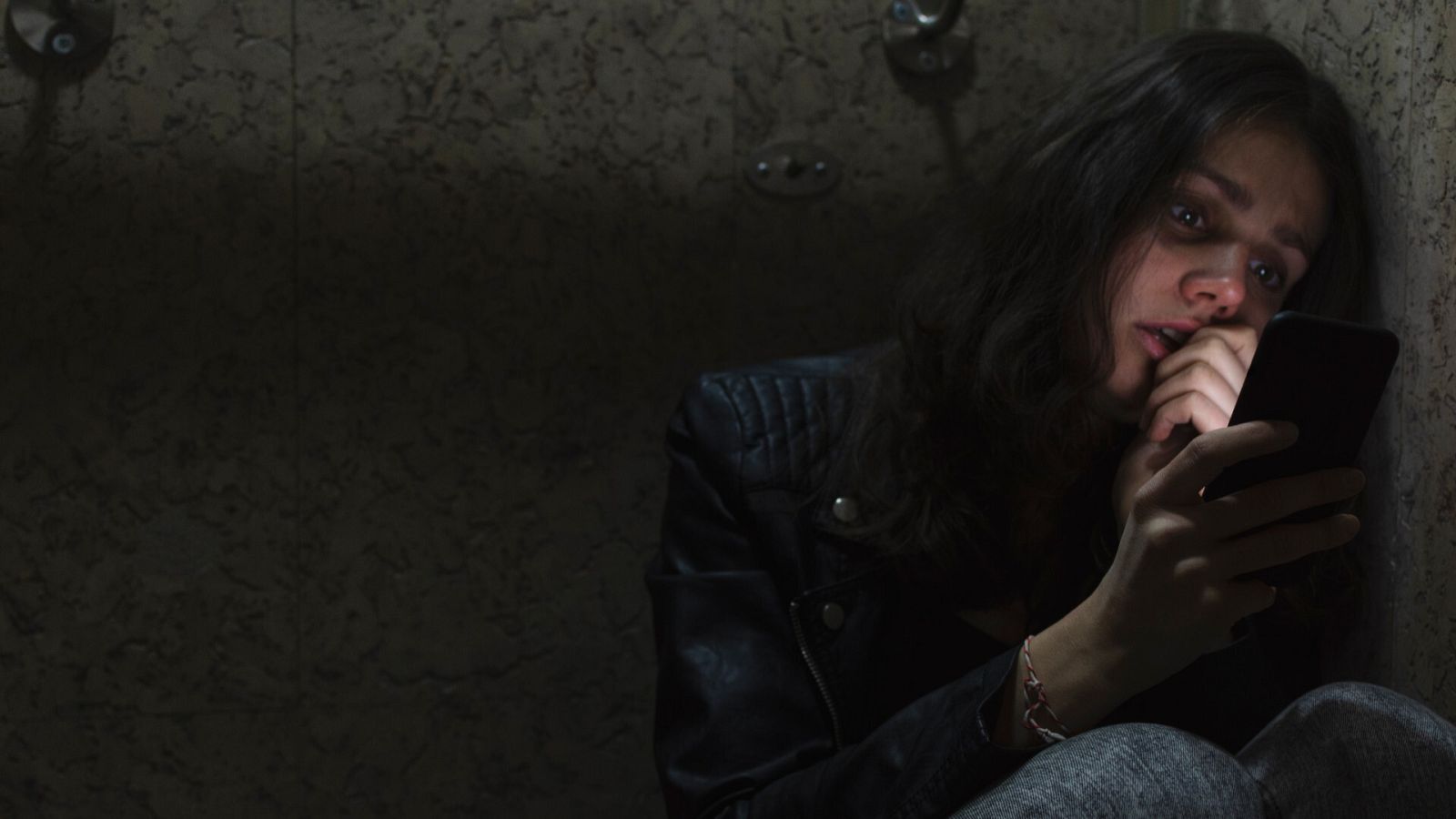 Una mujer asustada mira su teléfono