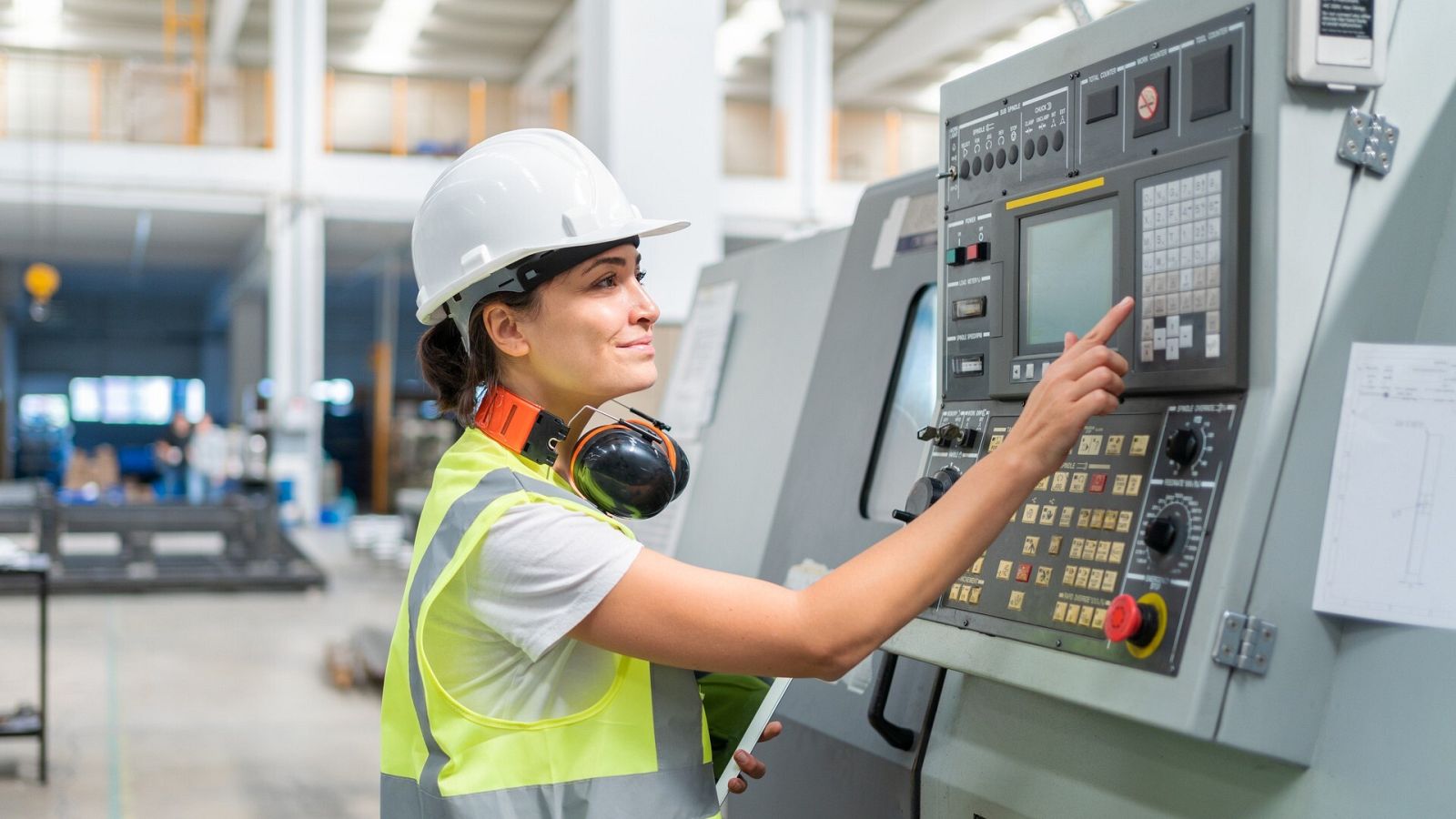 Una ingeniera calibra una máquina en una fábrica