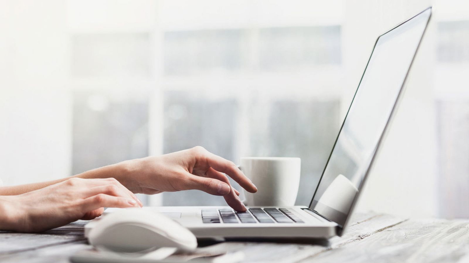 Una mujer escribe con un ordenador desde casa