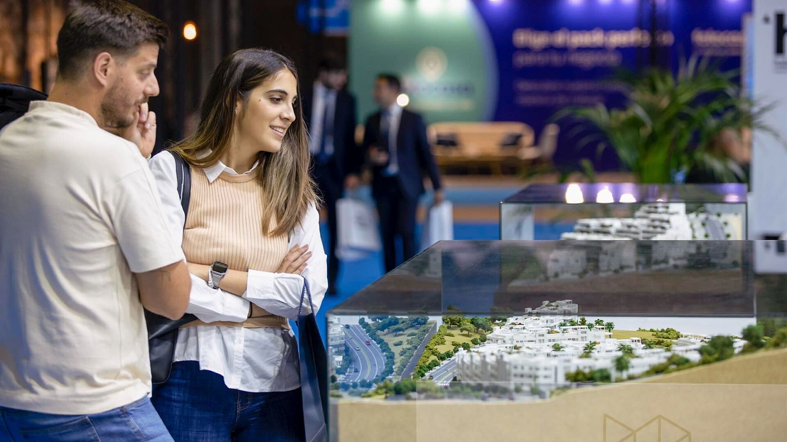 Una pareja joven observa una maqueta en un salón inmobiliario