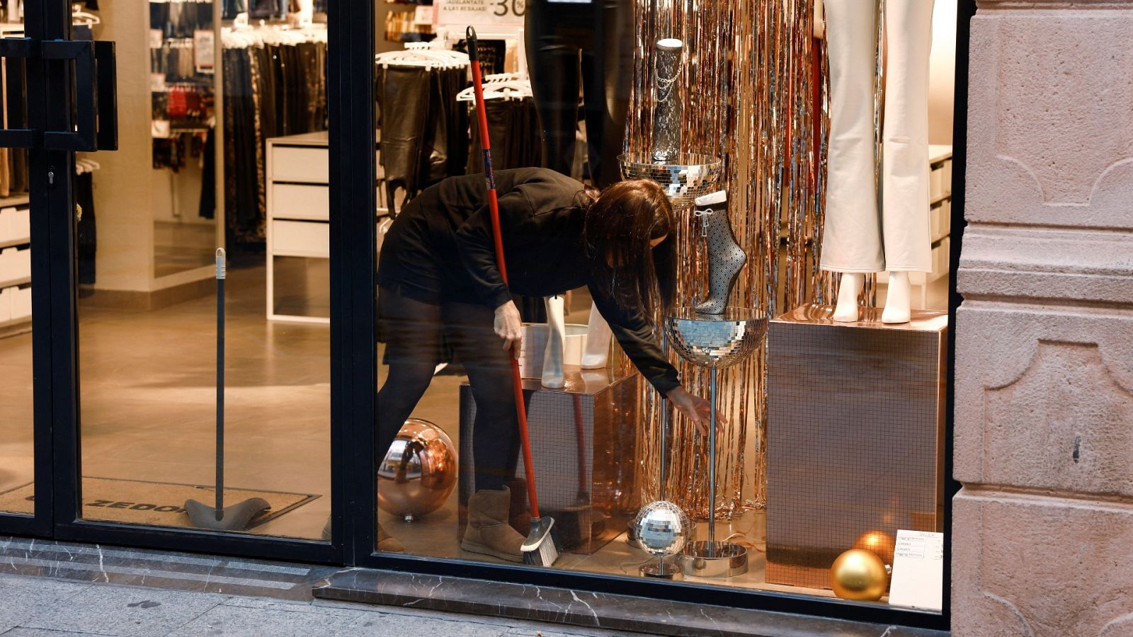 Una dependienta limpia un escaparate