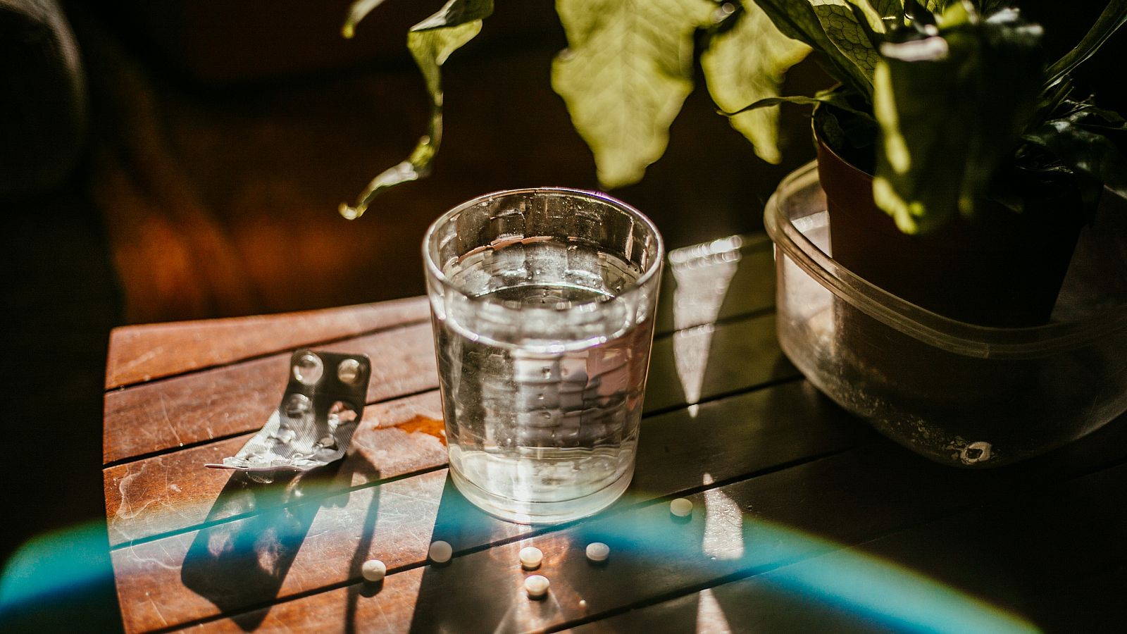 Un vaso de agua con un blíster de pastillas