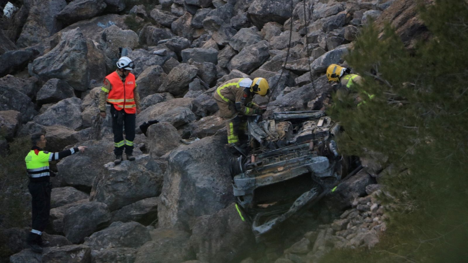 Efectius dels cossos d'emergències retiren un vehicle sinistrat i incendiat al Perelló
