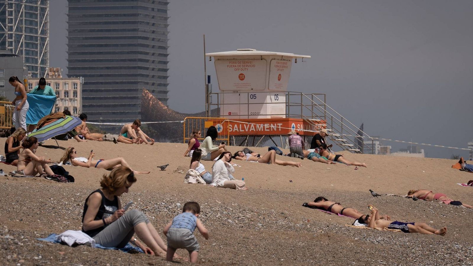 El tiempo hoy: varias personas toman el sol en la playa de la Barceloneta, en Cataluña