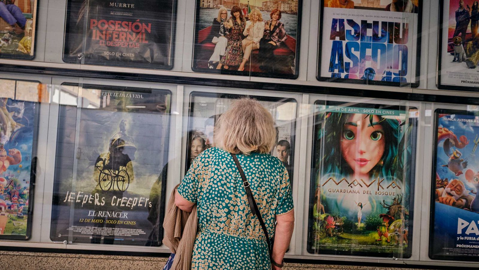 Una mujer mira los títulos de la cartelera