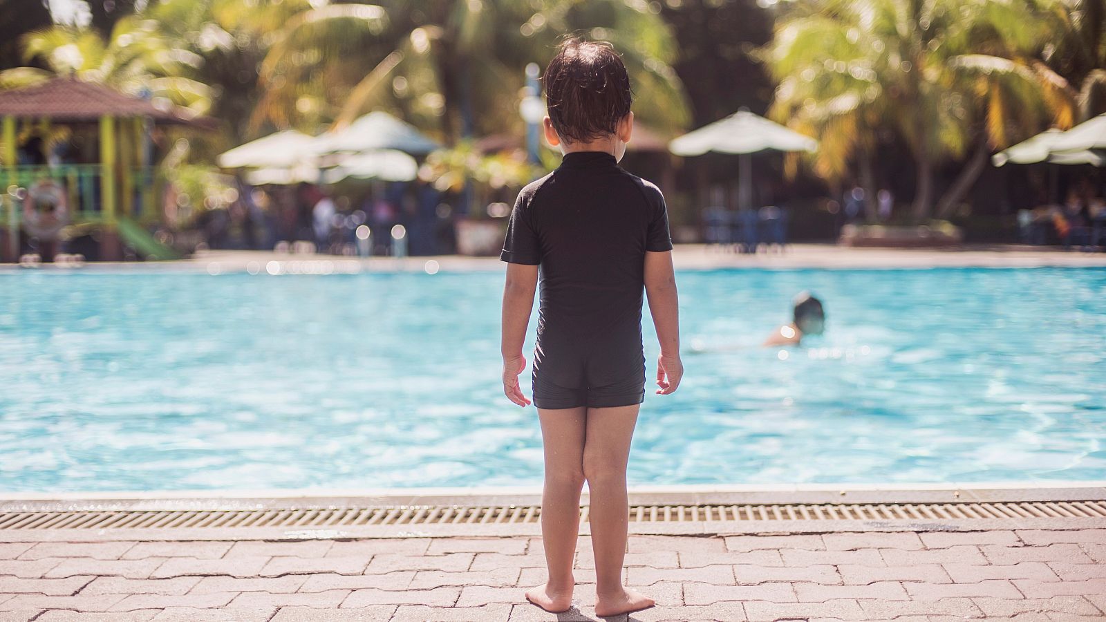 Imagen de archivo de un niño delante de una piscina