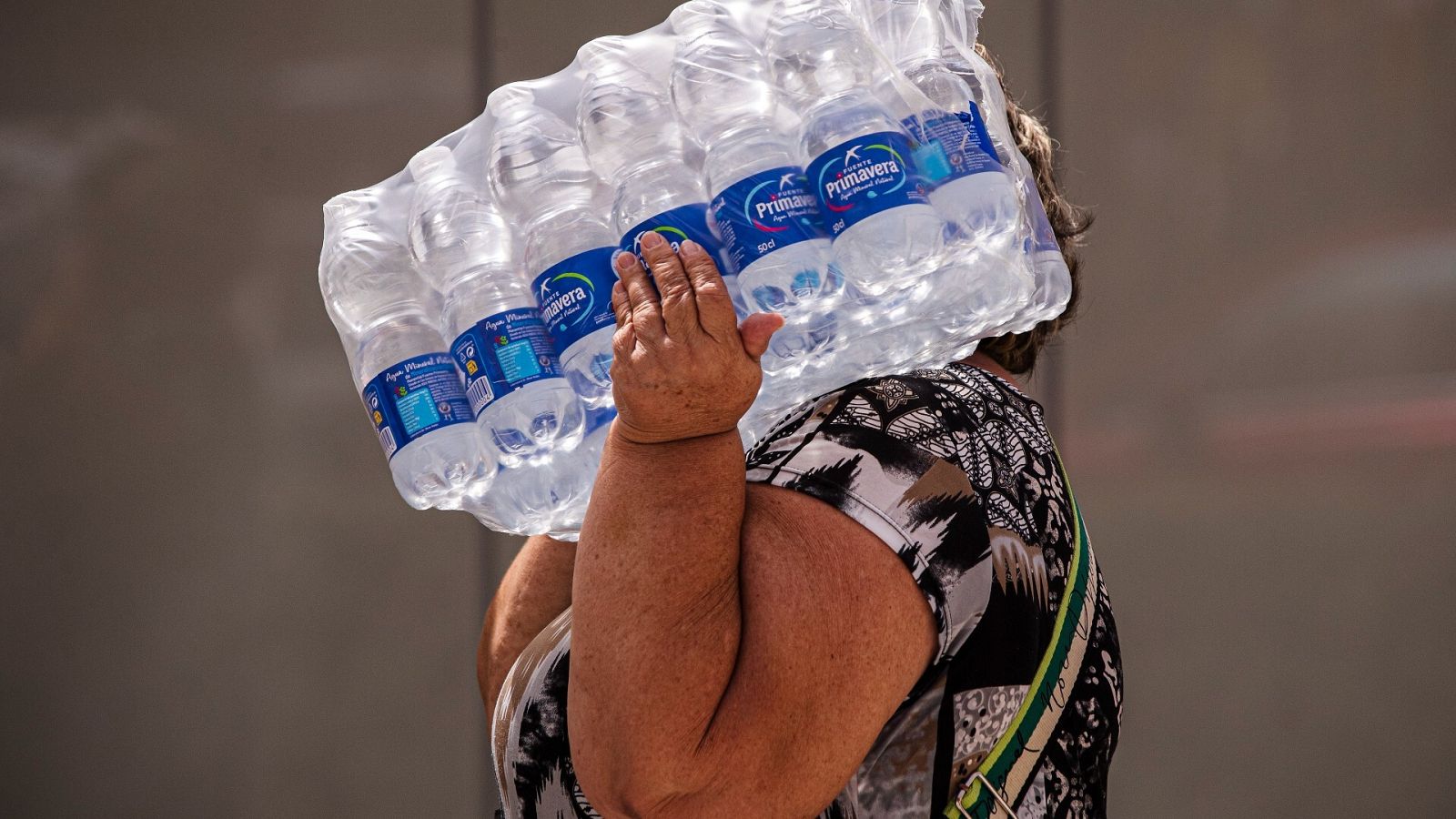 Una mujer lleva botellas de agua en la playa de la Malagueta