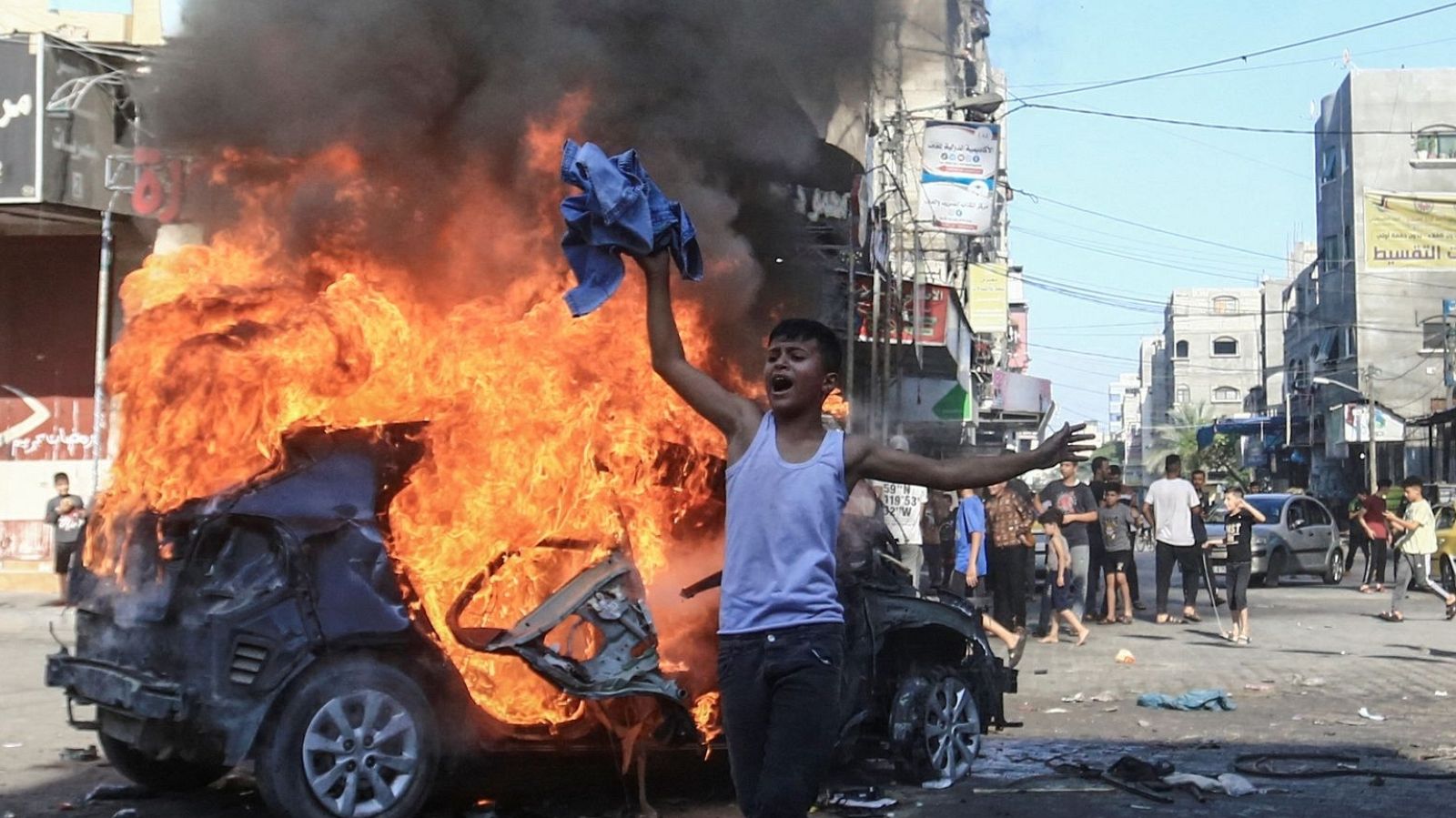 Un niño palestino pasa junto a un vehículo israelí en llamas