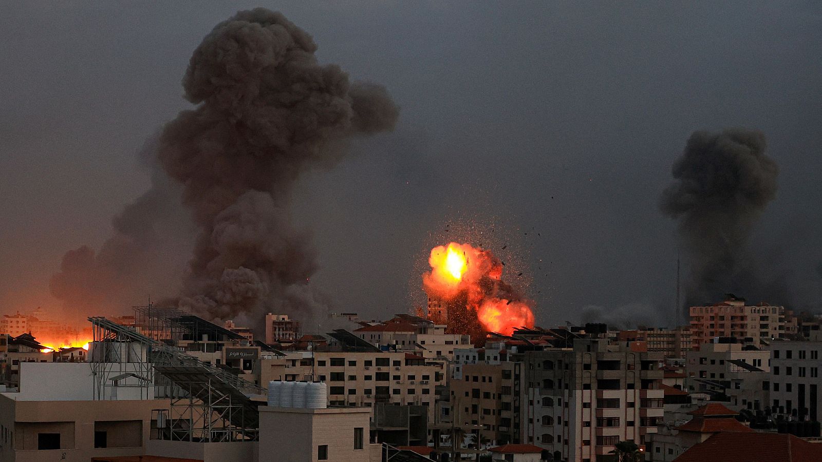 El humo se eleva y los escombros vuelan por los aires mientras cae la noche en la ciudad de Gaza durante los ataques aéreos israelíes del 9 de octubre de 2023