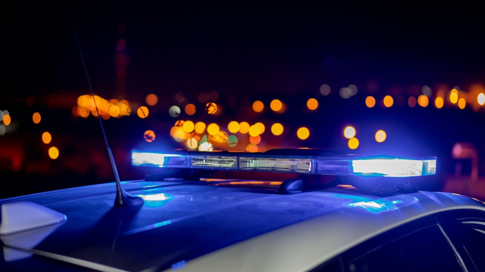 Detenido en Málaga por apuñalar a su mujer y su hija: Luces sobre un coche patrulla de la policía, en una imagen de archivo