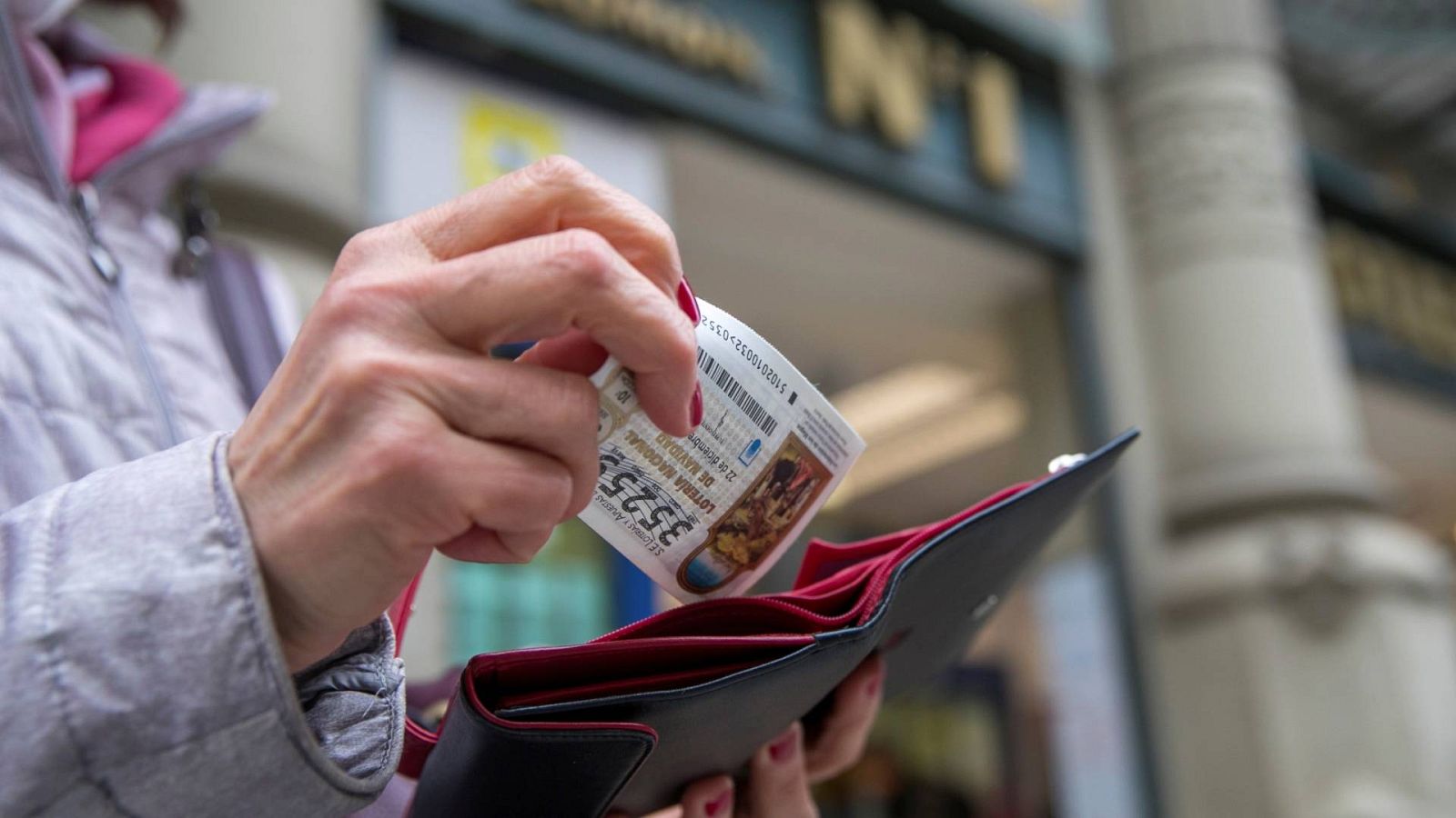 Lotería de Navidad: una mujer guarda en la cartera el décimo de lotería de Navidad comprado