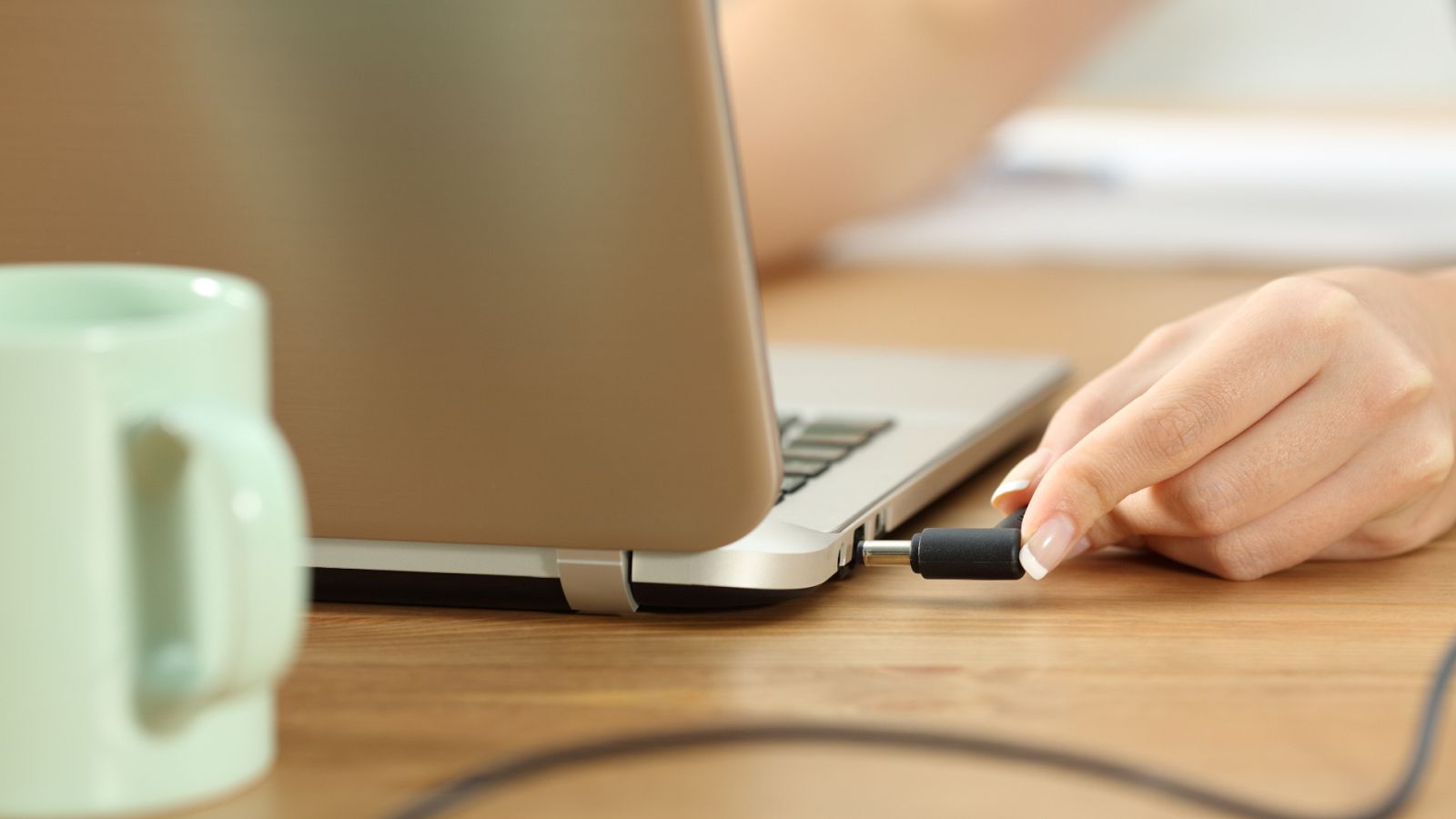 Una persona conecta el cargador de un ordenador