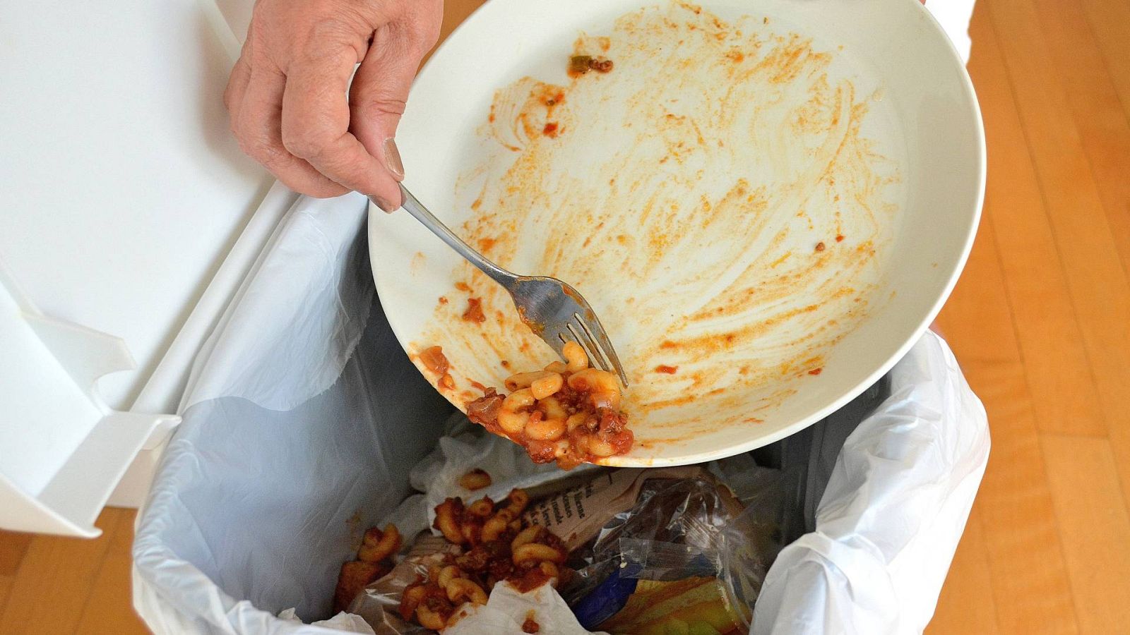 Una mujer tira a la basura los alimentos que han sobrado de un plato