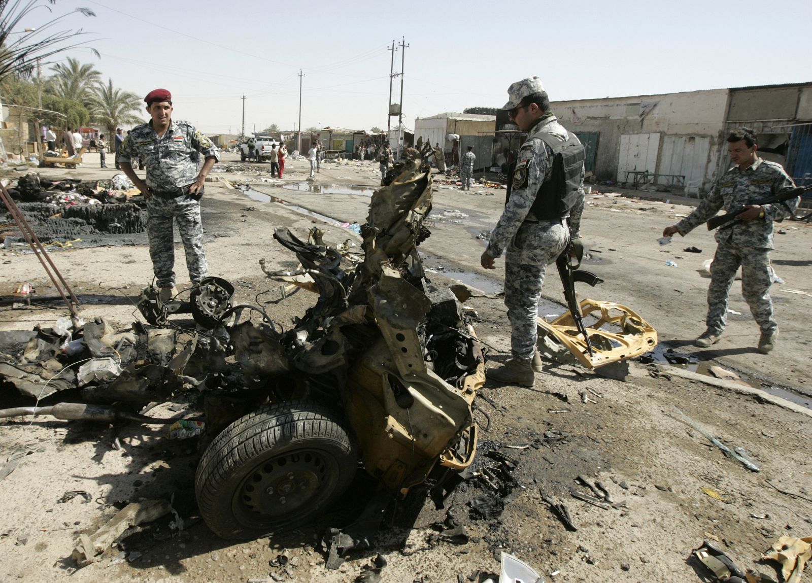 Policemen inspect the wreckage of a vehicle used in a car bomb attack in Baghdad