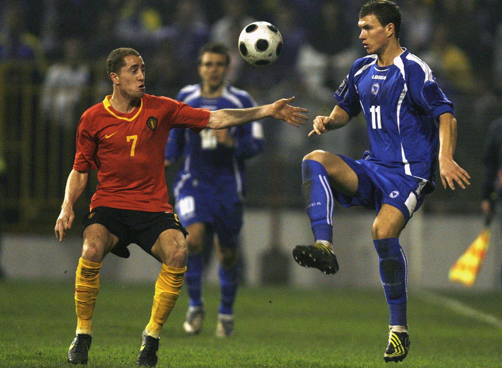 Edin Dzeko de Bosnia disputa u n balón con el belga Gill Swerts.