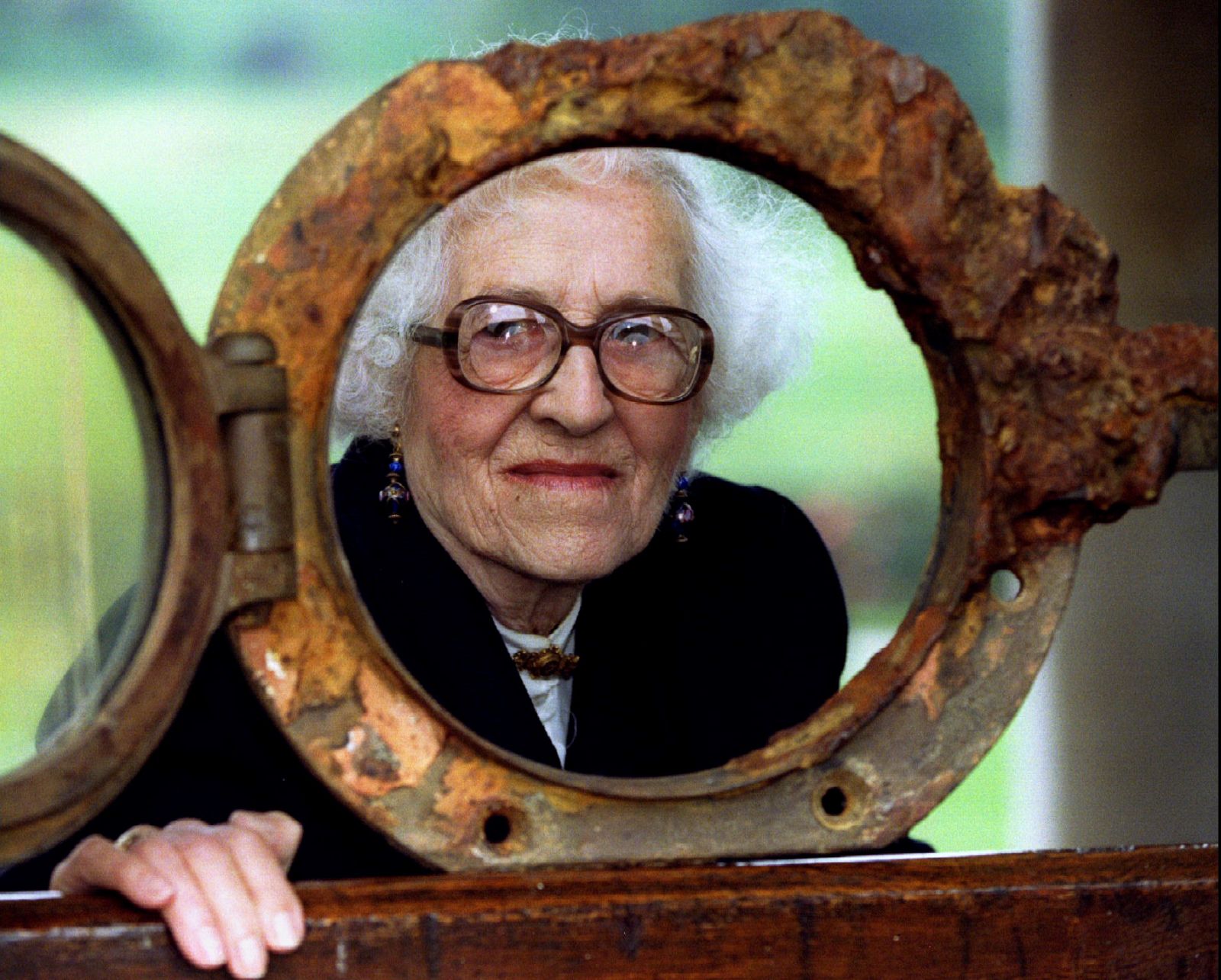Millvina Dean,82, youngest survivor of the Titanic which sank in 1912, peers through a porthole from..