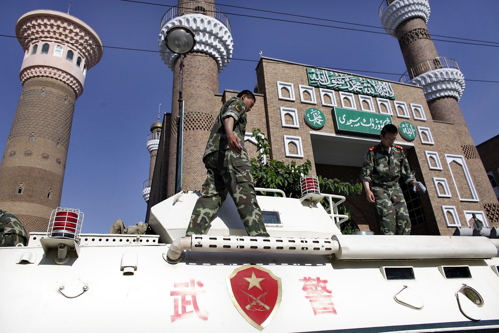Chinese soldiers clean armoured personnel carrier as it waits on standby outside main mosque in Urumqi