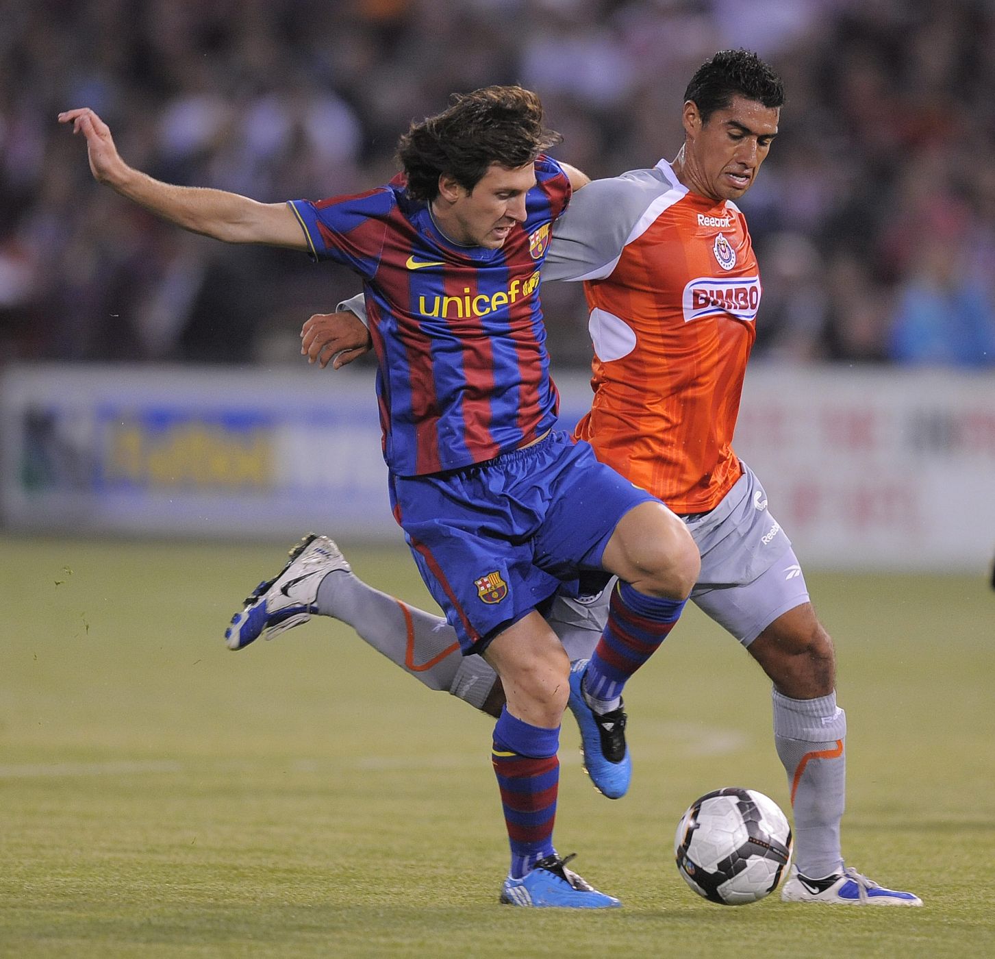 La estrella del FC Barcelona, Leo Messi, disputa un balón con un jugador del Chivas.