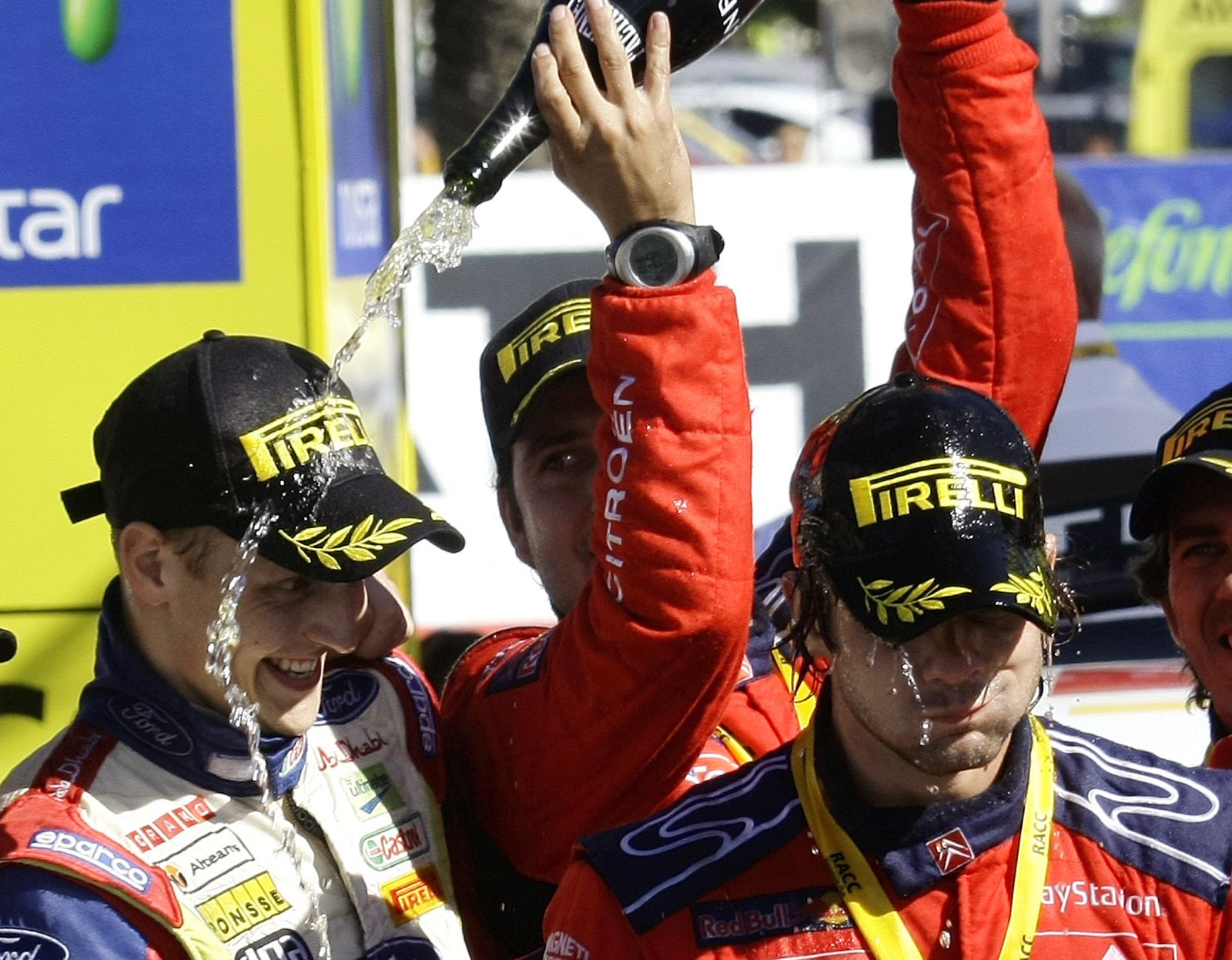 Co-driver Daniel Elena pours champagne over Sebastien Loeb of France and Mikko Hirvonen from Finland on podium after winning the Rally of Catalunya in Salou