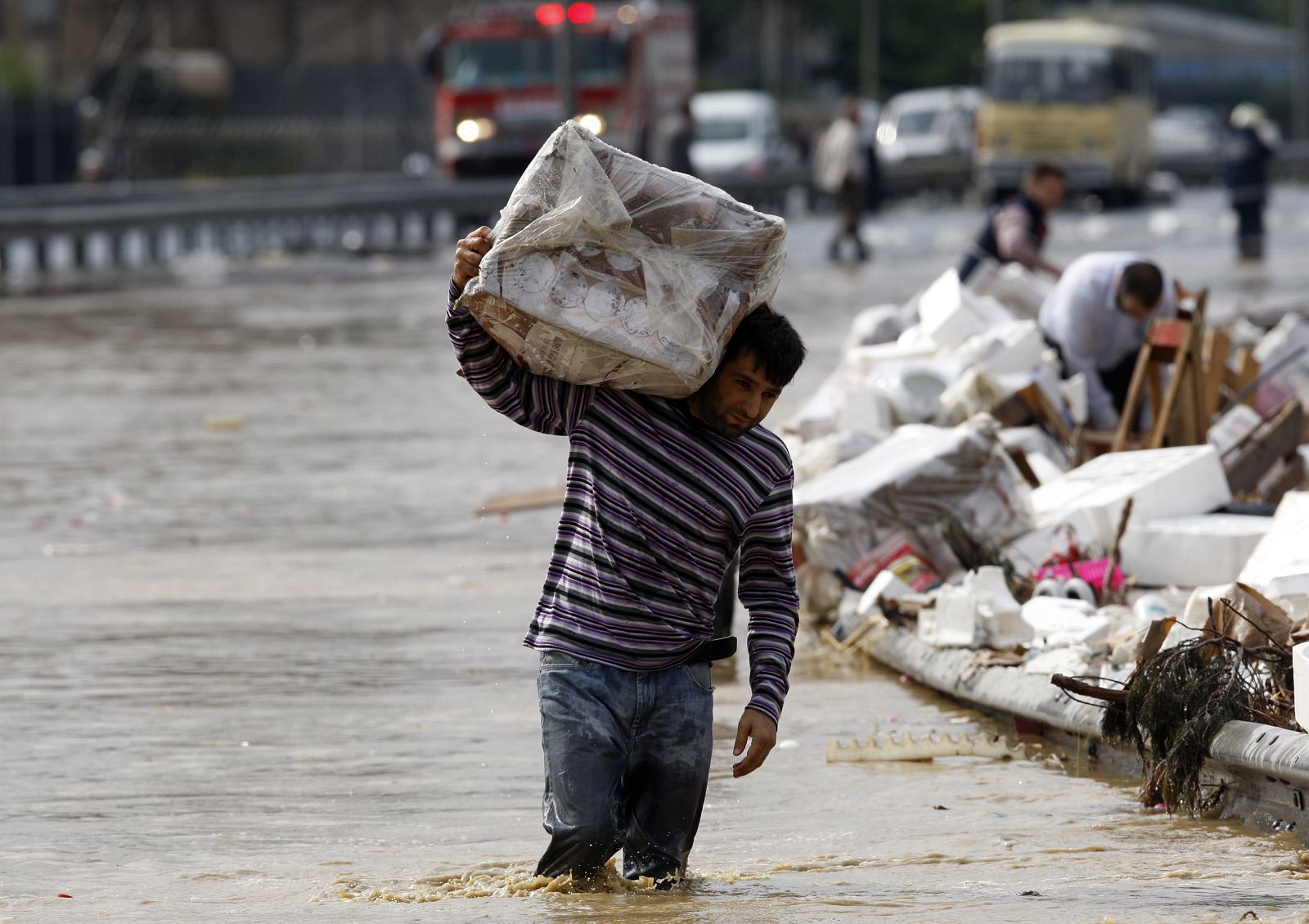 A man walks on a flooded highway as he carries a parcel in Istanbul