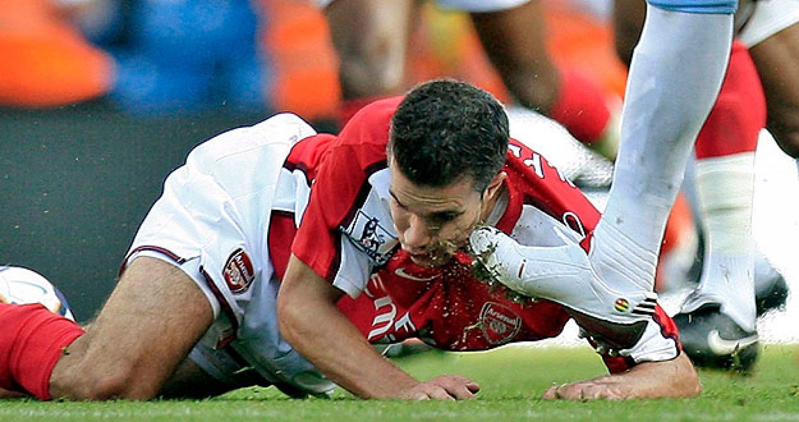 El delantero del Arsenal Robin Van Persie recibe una patada del jugador del Manchester City Adebayor.