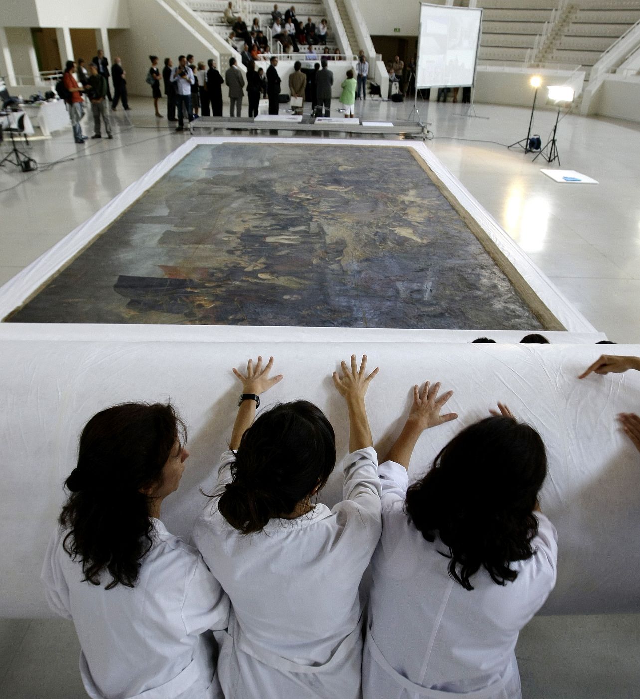 Tres restauradoras cubren con un papel protector una pintura