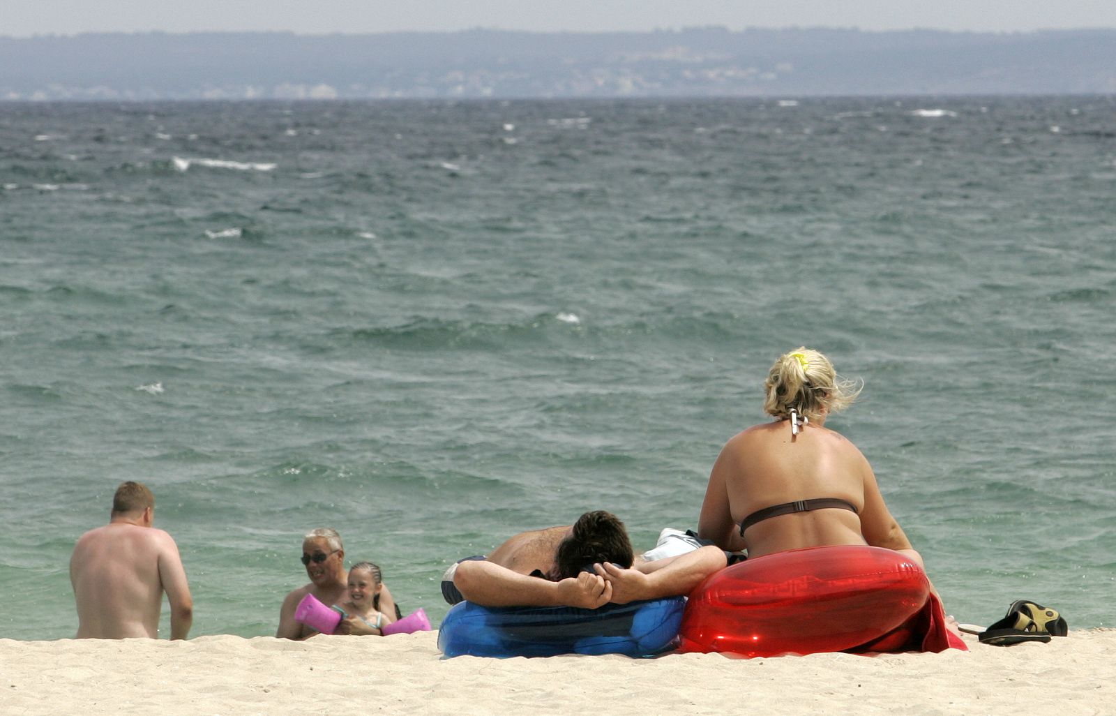Tourists sunbathe at a beach in Palmanova, in the Spanish island of Mallorca