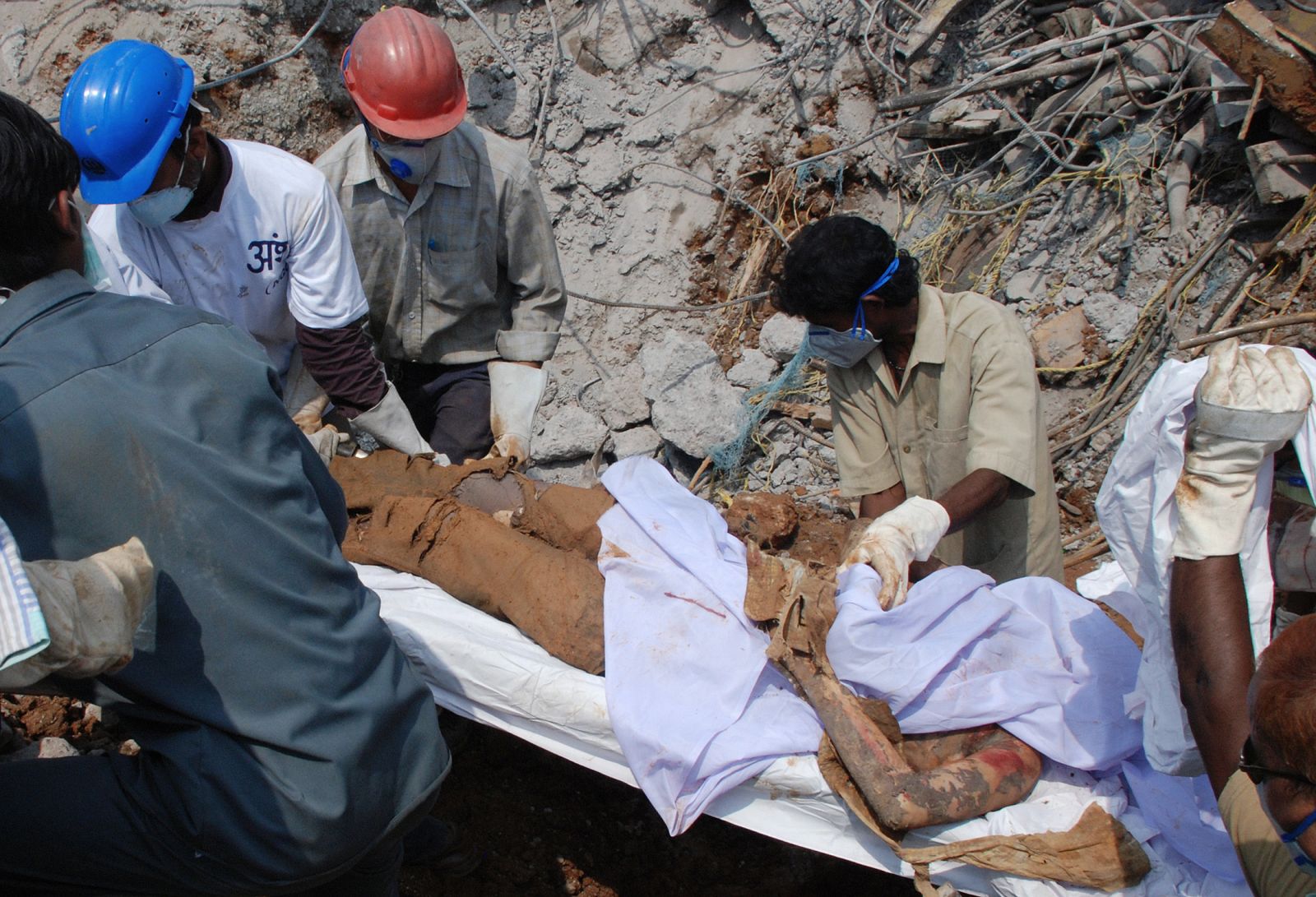 Los servicios de rescate transportan un cuerpo después del desplome de una chimenea en la central Balco Nagar