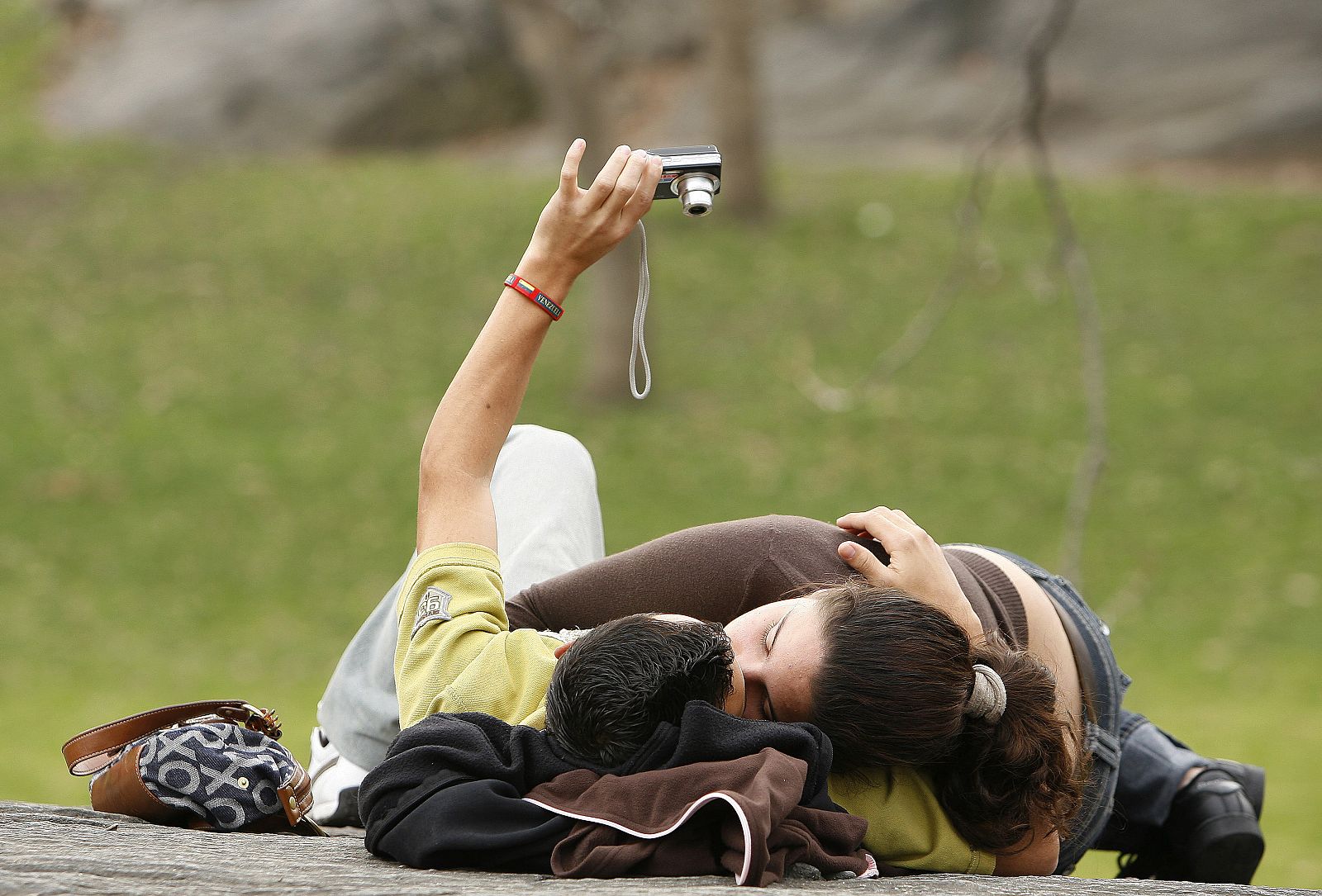 Una pareja de jóvenes se besa en un parque