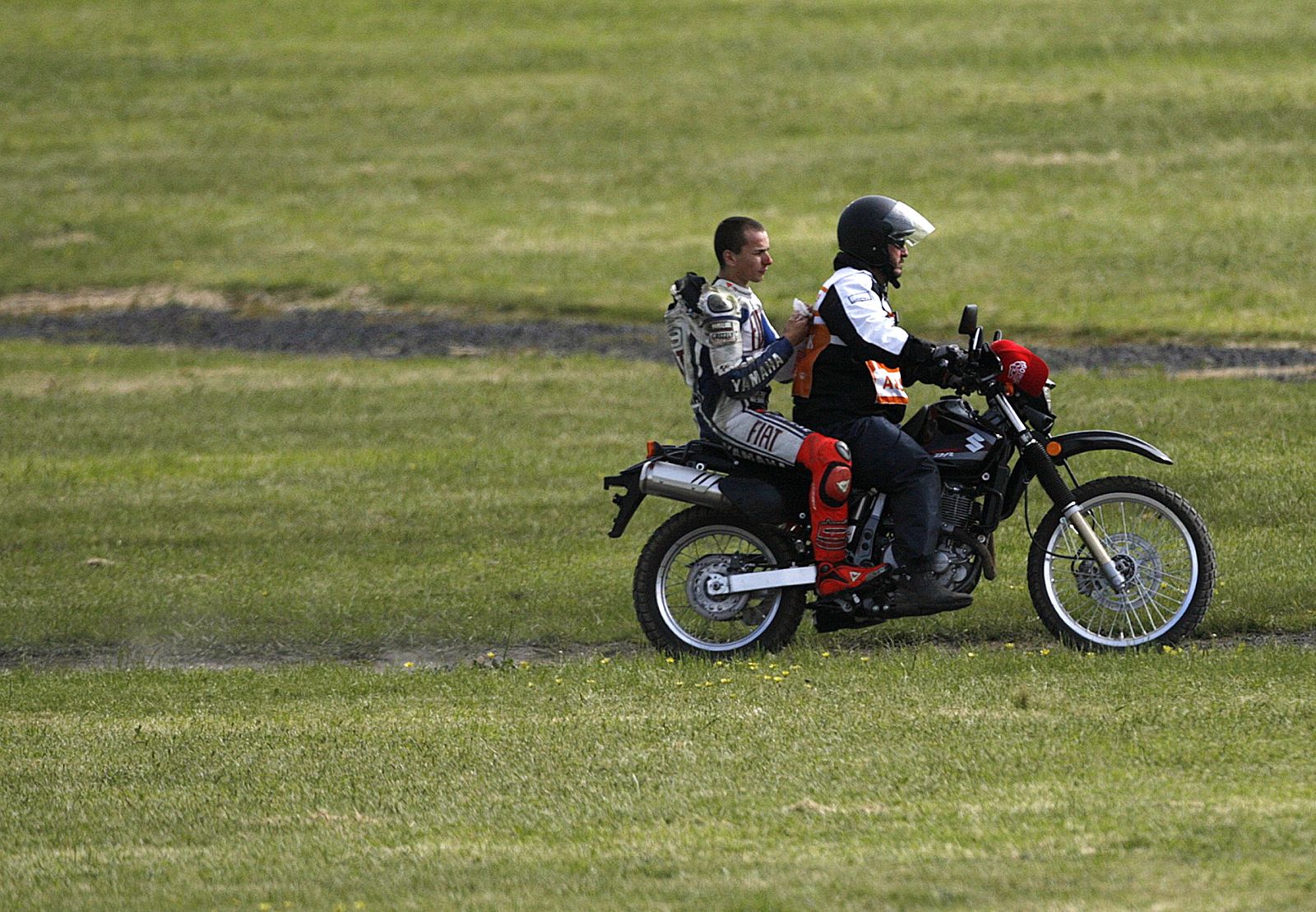 Yamaha Moto GP rider Lorenzo gets a lift on the back of an official's bike after crashing in the Australian Grand Prix at Phillip Island