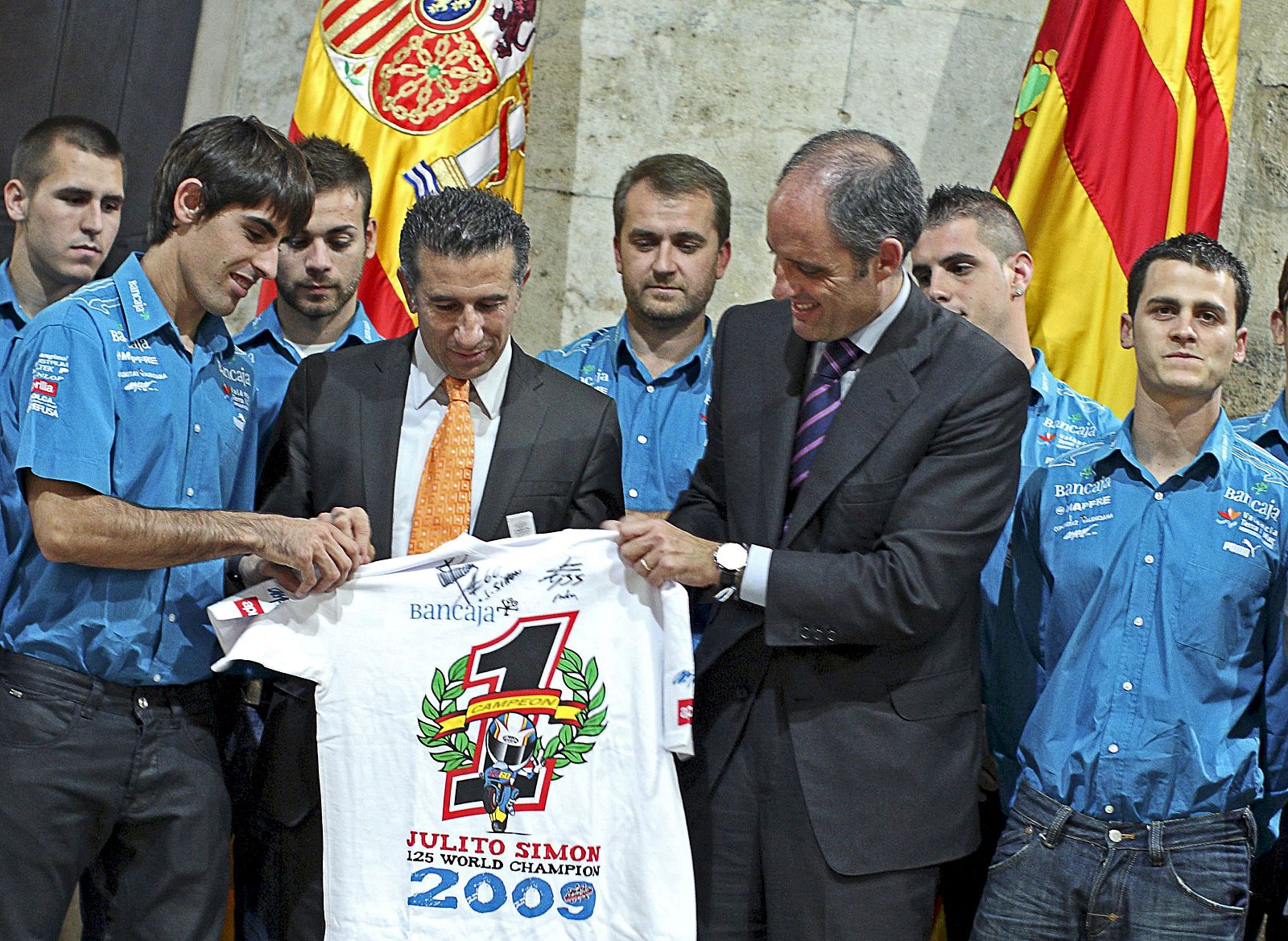 El president de la Generalitat, Francisco Camps, recibe de manos del piloto Julián Simón, campeón del mundo 2009 de 125 cc., y su director de equipo el ex piloto Jorge Martínez "Aspar", una camiseta conmemorativa