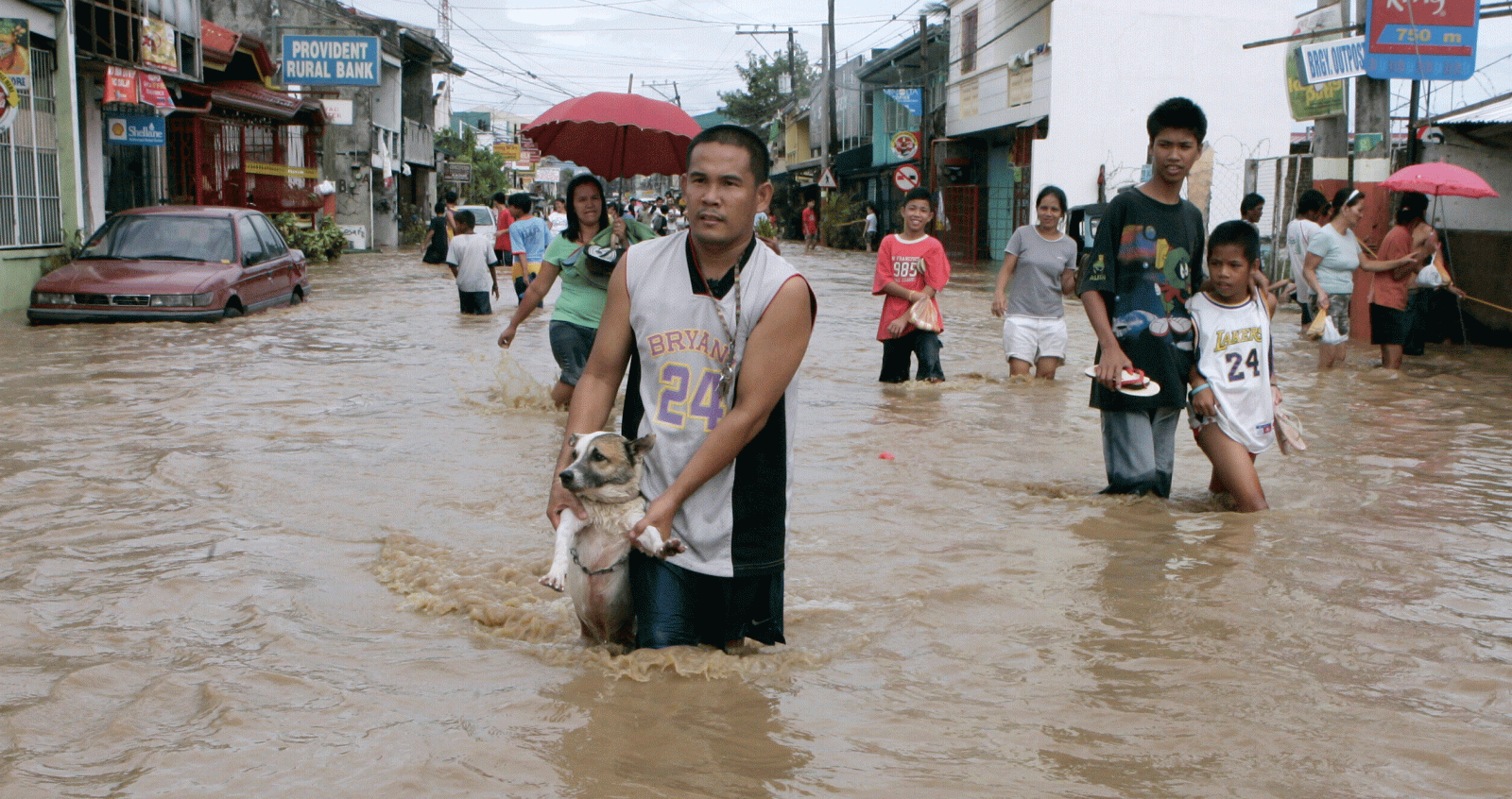 Un hombres sostiene a su perro mientras en mitad de una calle anegada por las inundaciones del tifón "Marinae" en la provincia filipina de Laguna.