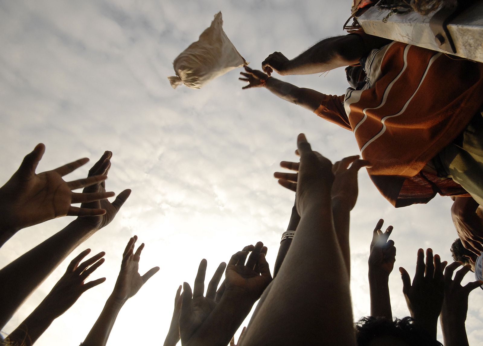 Flood-affected people raise their hands to collect food at Alampur village