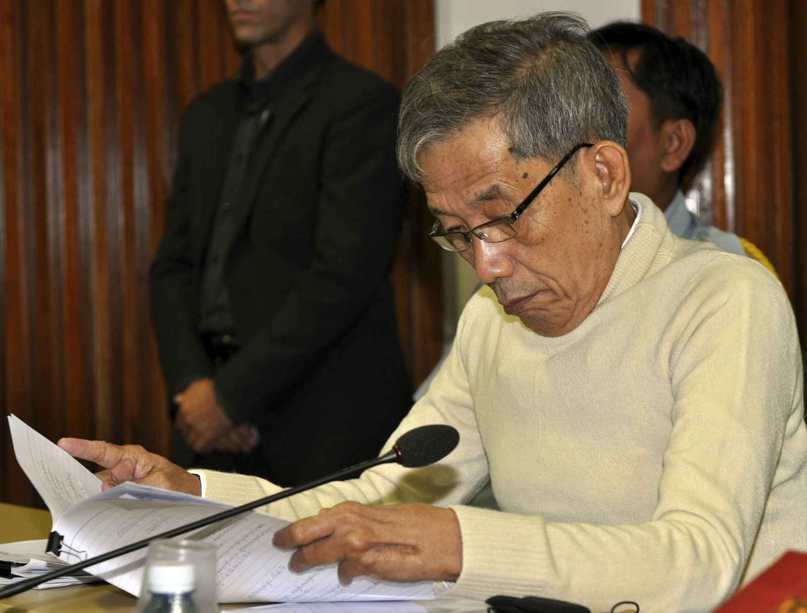 Chief Khmer Rouge interrogator Duch reads a document during closing arguments at his trial by a U.N.-backed tribunal at the ECCC on the outskirts of Phnom Penh