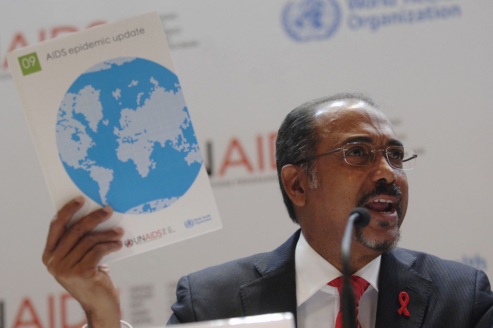 UNAIDS executive director Michel Sidibe holds a report during a news conference in Shanghai