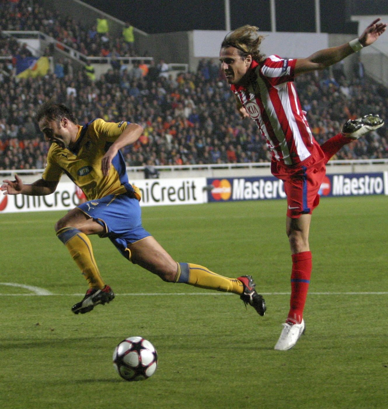 Atletico Madrid's Diego Forlan fights for the ball with APOEL Nicosia's Savvas Poursaitides during their Champions League match at the GSP Stadium in Nicosia