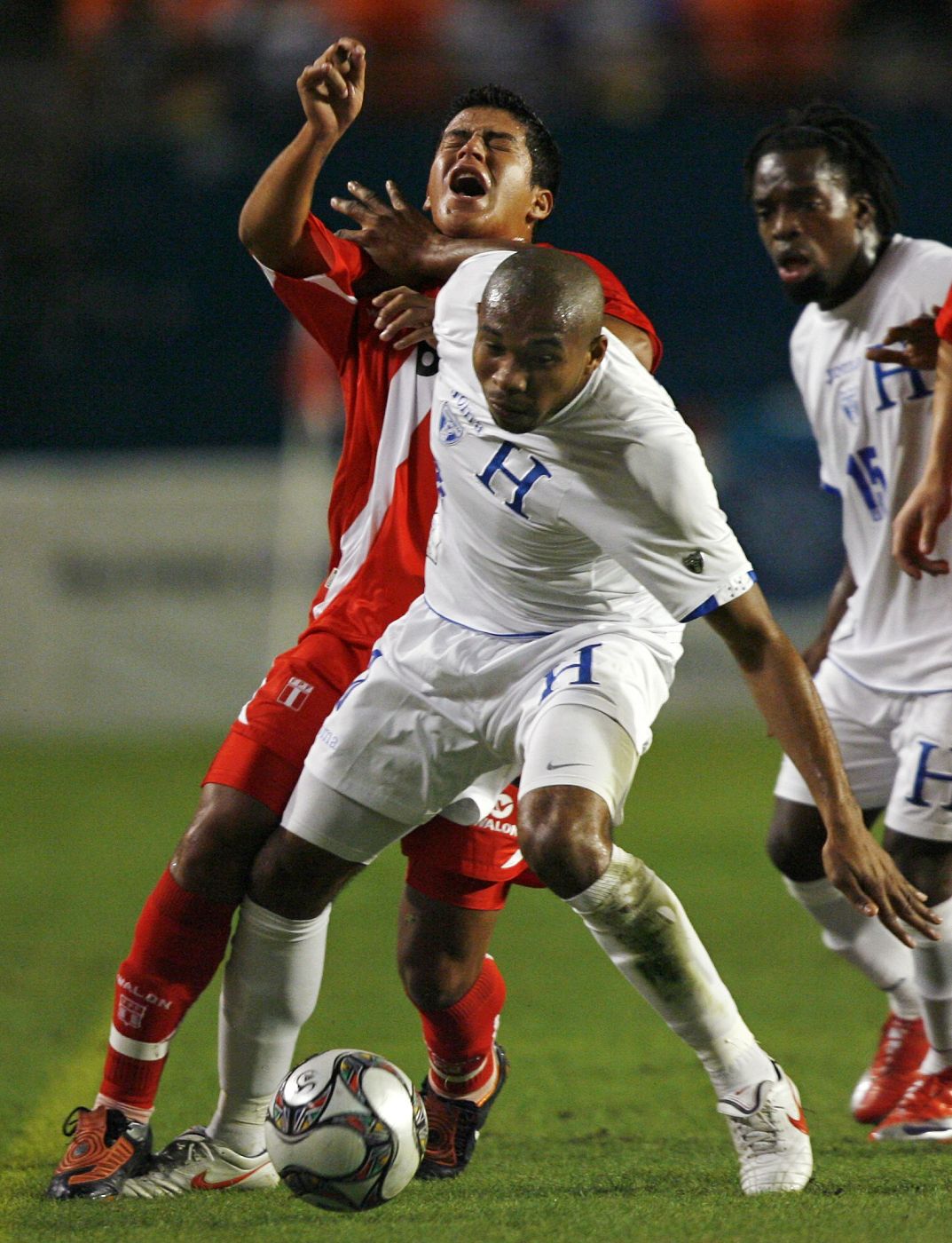 Marcio Valverde of Peru is fouled by Wilson Palacios of Honduras as Walter Martinez looks on during first half of their friendly exhibition soccer match in Miami