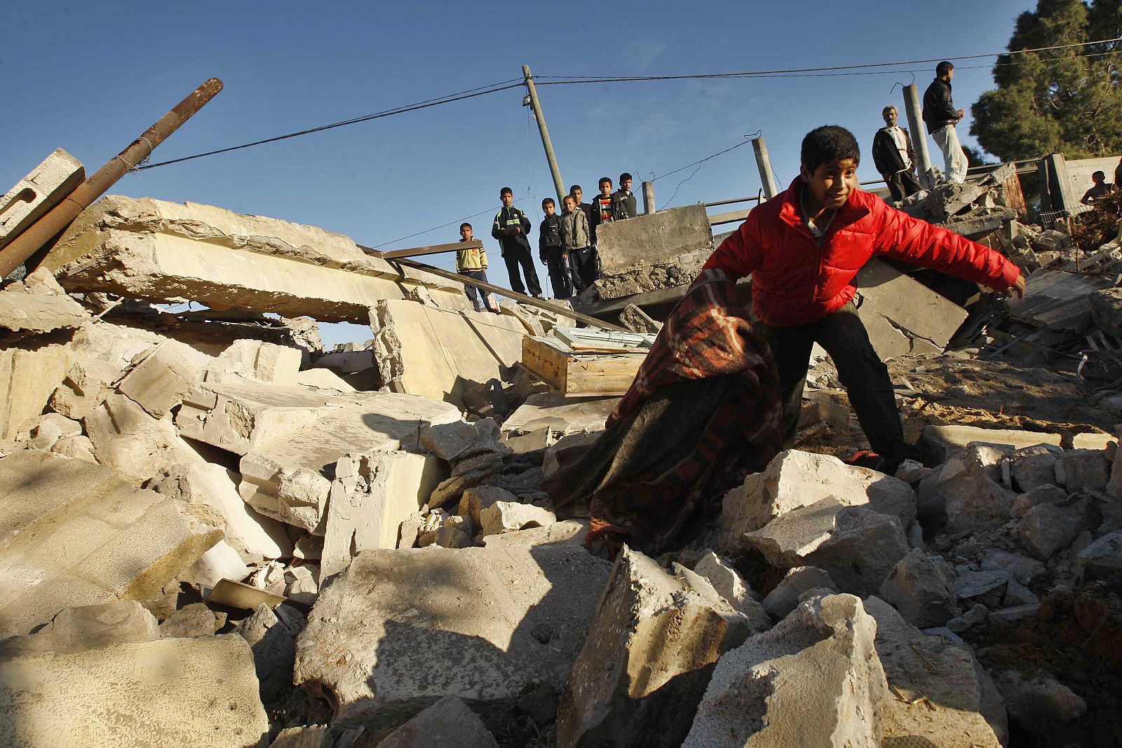 Palestinian boy walks atop a building destroyed in an Israeli air strike in Khan Younis