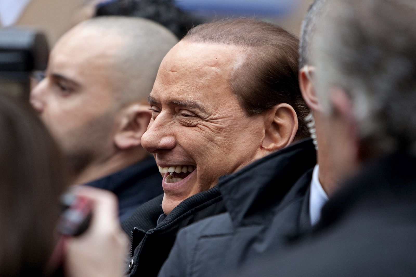 Italy's Prime Minister Berlusconi smiles as he arrives escorted by his bodyguards in his private residence at Grazioli palace in Rome