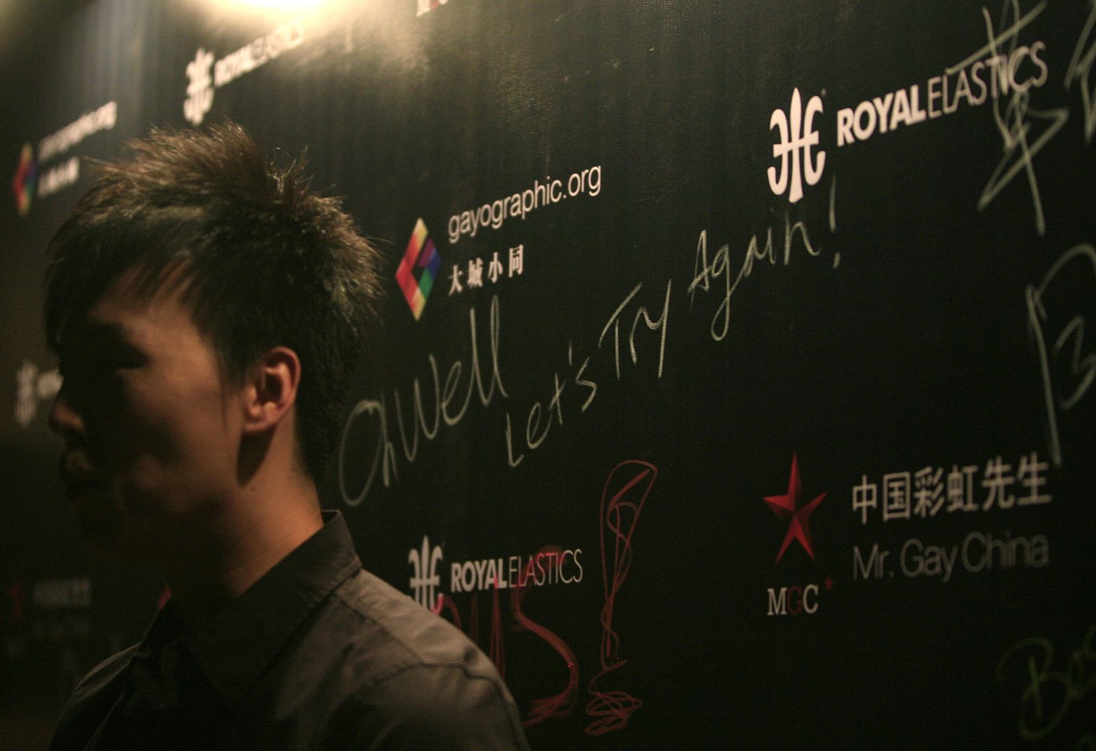 A participant for the "Mr. Gay China" pageant stands next to a poster after the pageant was shut down by police in Beijing