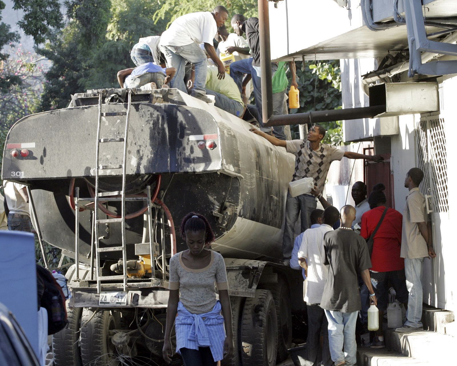 Looters siphon gasoline from a wrecked tanker in Port-au-Prince