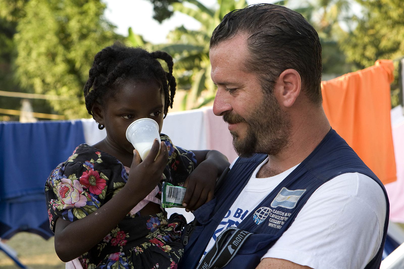 A girl is held by an aid worker at a small Argentinian clinic in Leogane