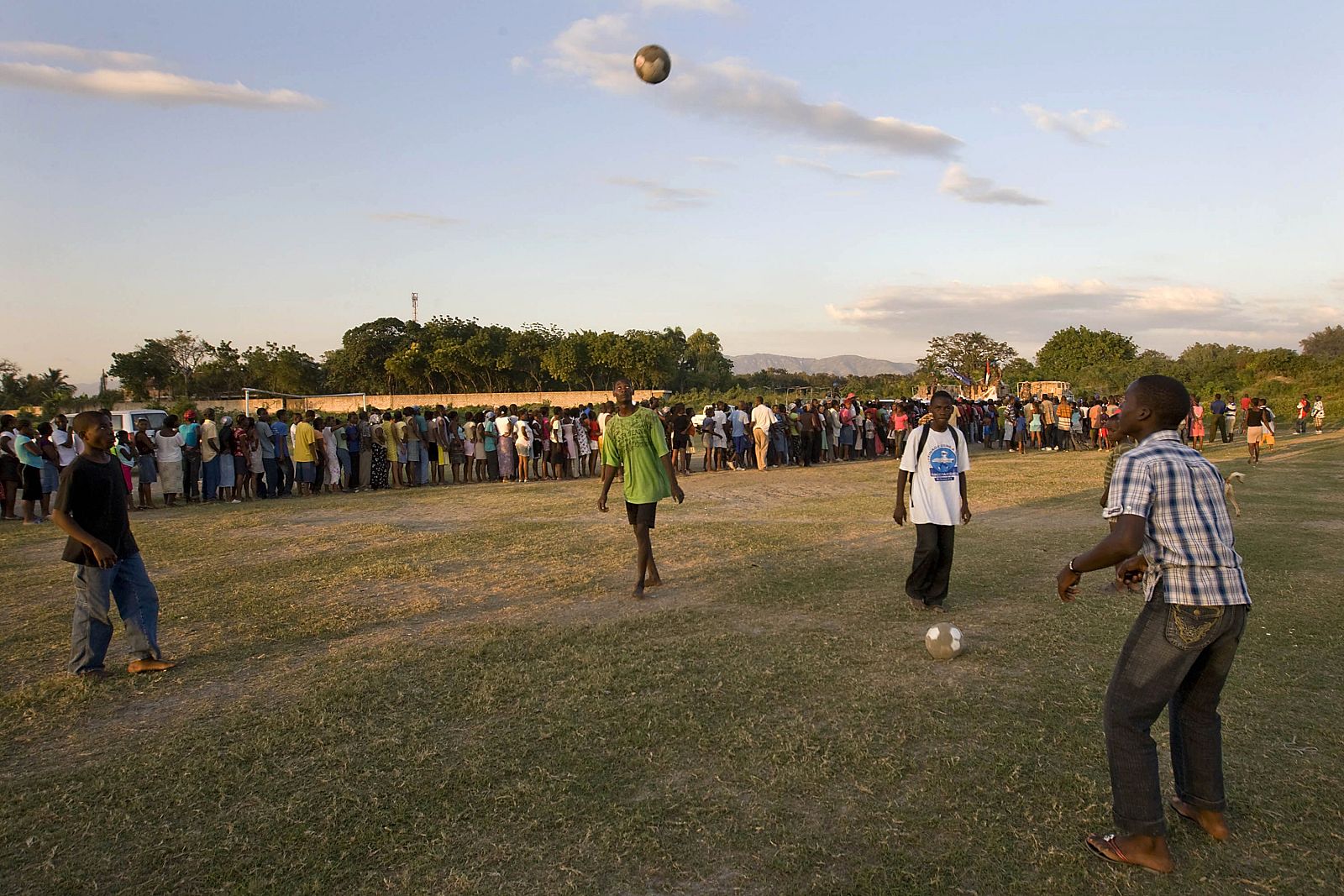 Children play soccer in front of internally displaced Haitians lining up for food during a U.N. distribution in Port-au-Prince