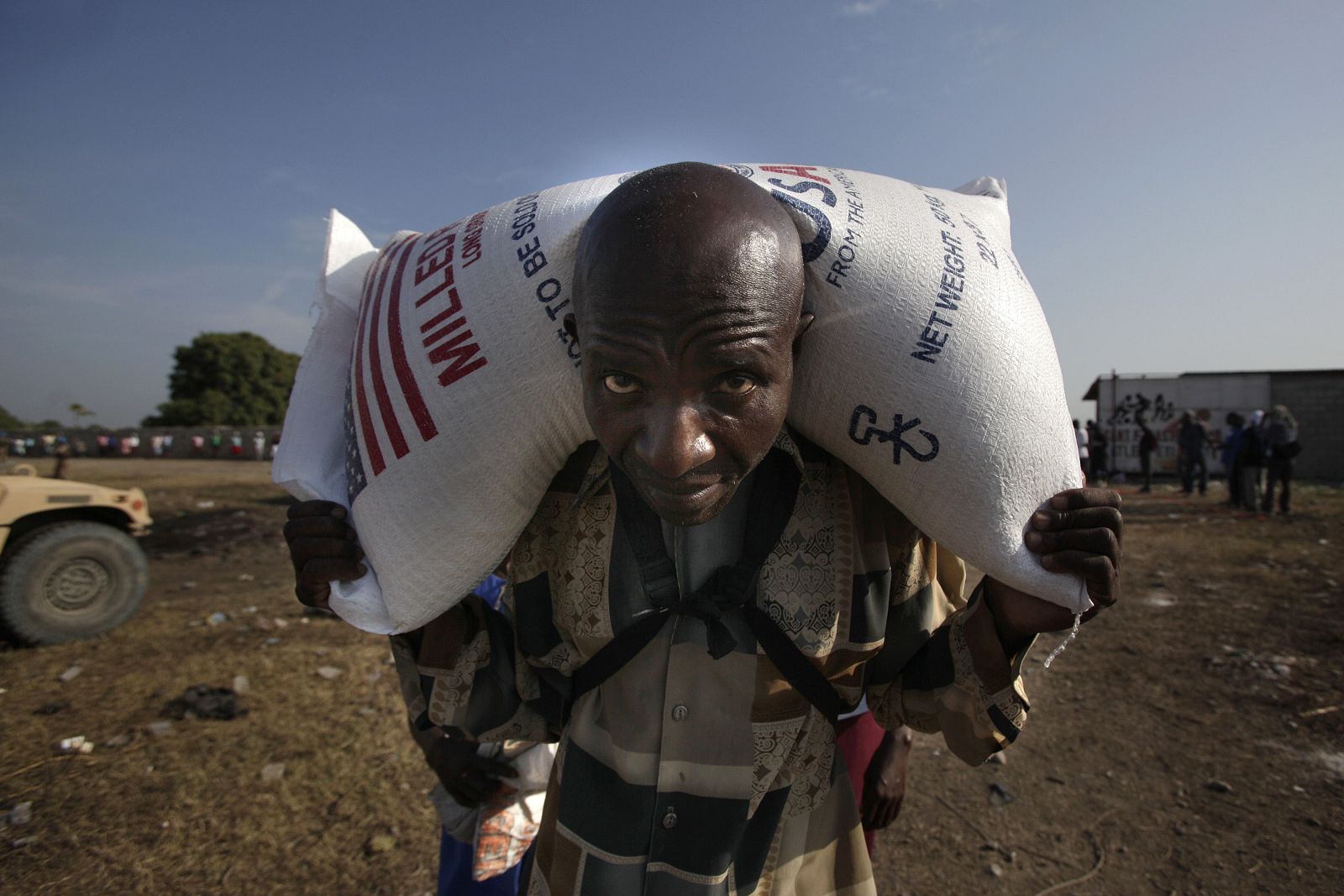 Haitian man carries a sack of rice during a food distribution in Port-au-Prince