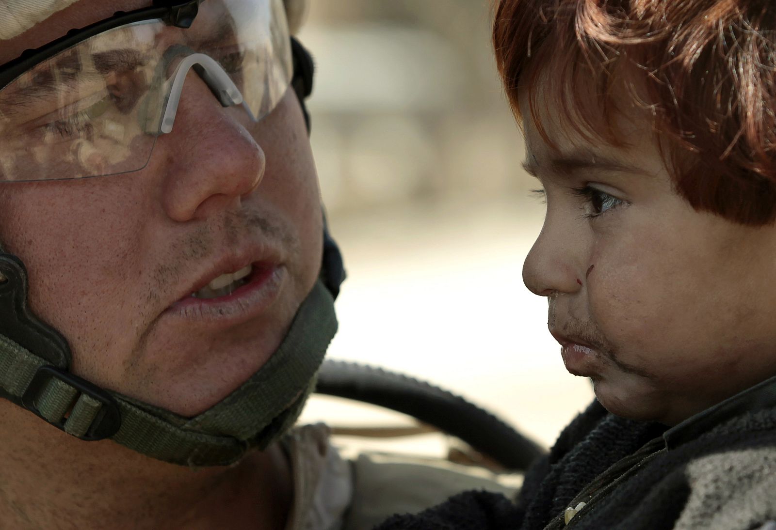 U.S. Marine Gunnery Sergeant Brandon Dickinson from Bravo Company of the 1st Battalion, 6th Marines holds a toddler in the town of Marjah, in Nad Ali district of Helmand province