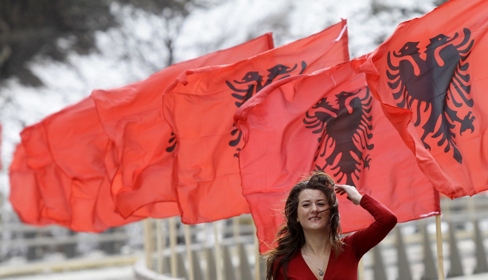 A woman walks past Albanian national flags which have been put up ahead of the second anniversary of Kosovo's independence in the town of Kacanik