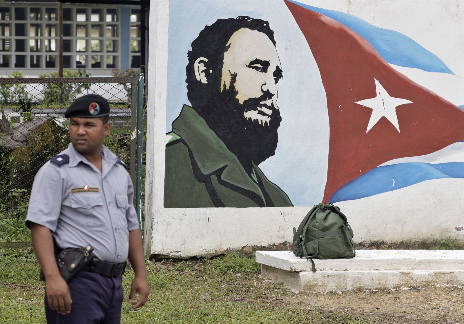 Un policía permanece al lado de un imagen de Fidel Castro y la bandera cubana