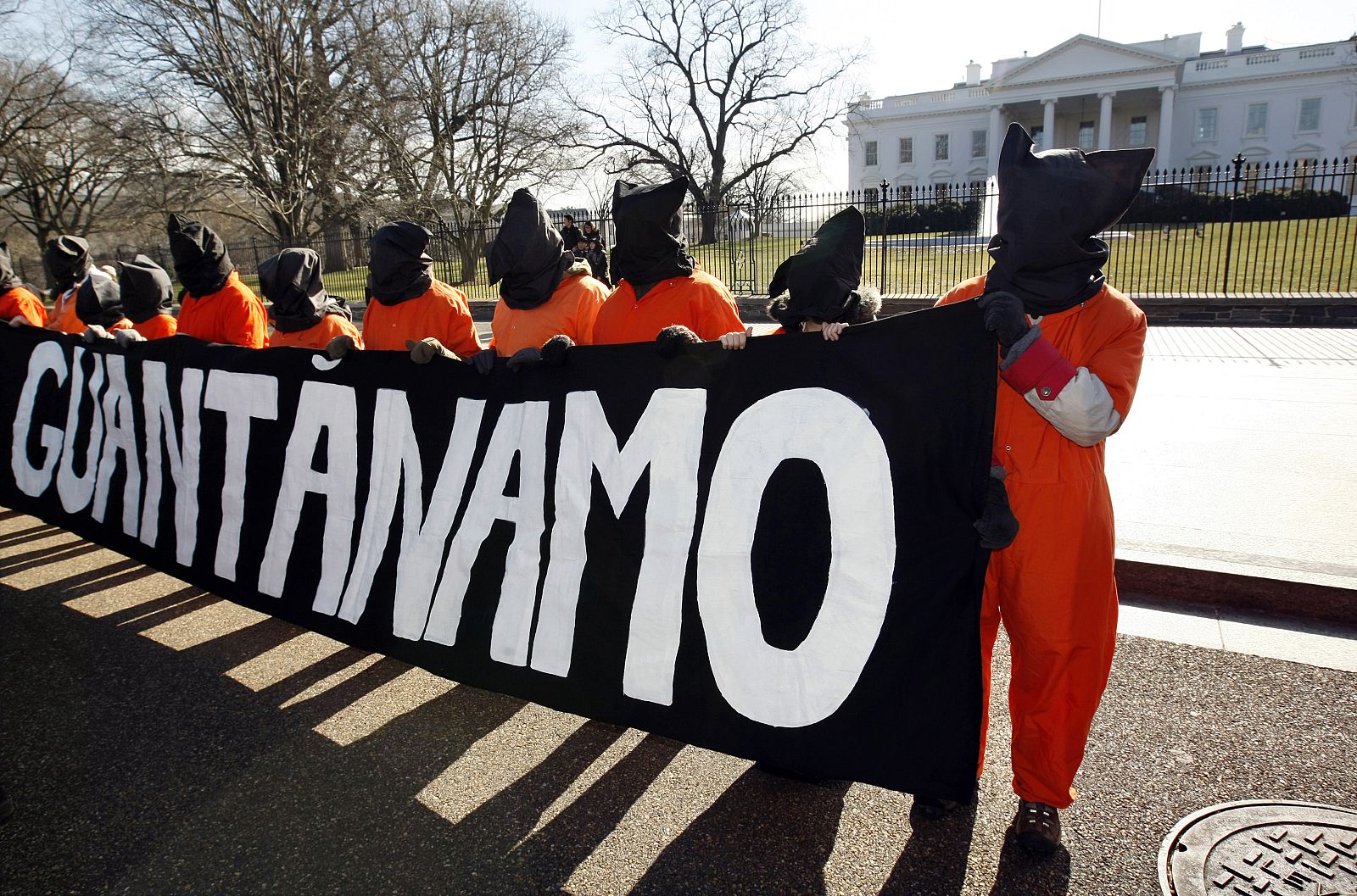 Hooded protesters dressed as Guantanamo Bay detainees demonstrate in front of the White House in Washington