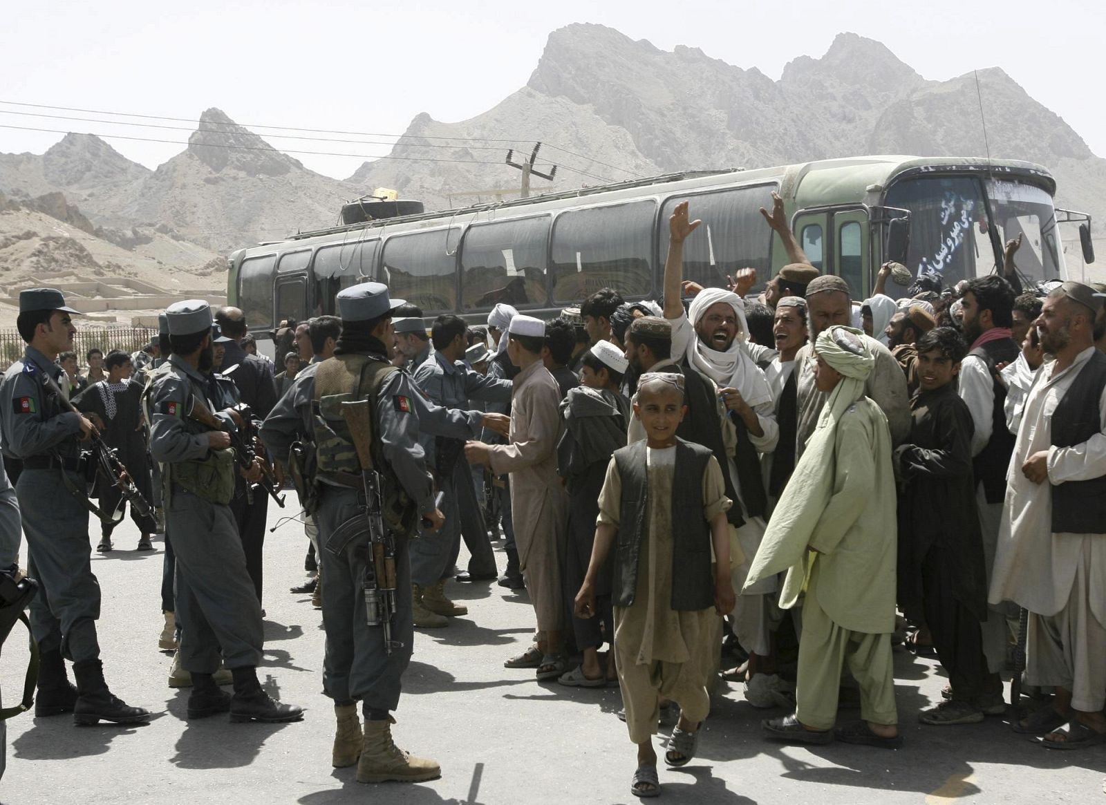 Afghan police and onlookers gather around a bus which was fired upon by foreign forces in Kandahar