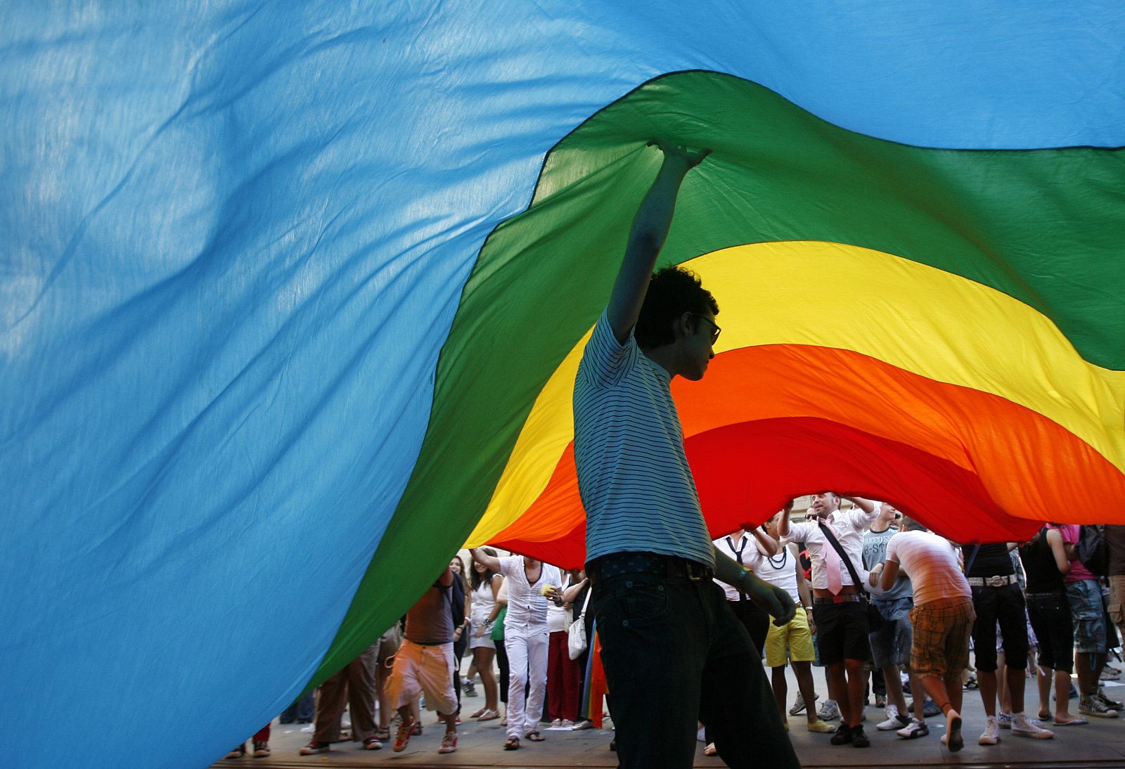 People hold a rainbow flag as they take part in a Gay Pride parade in downtown Seville